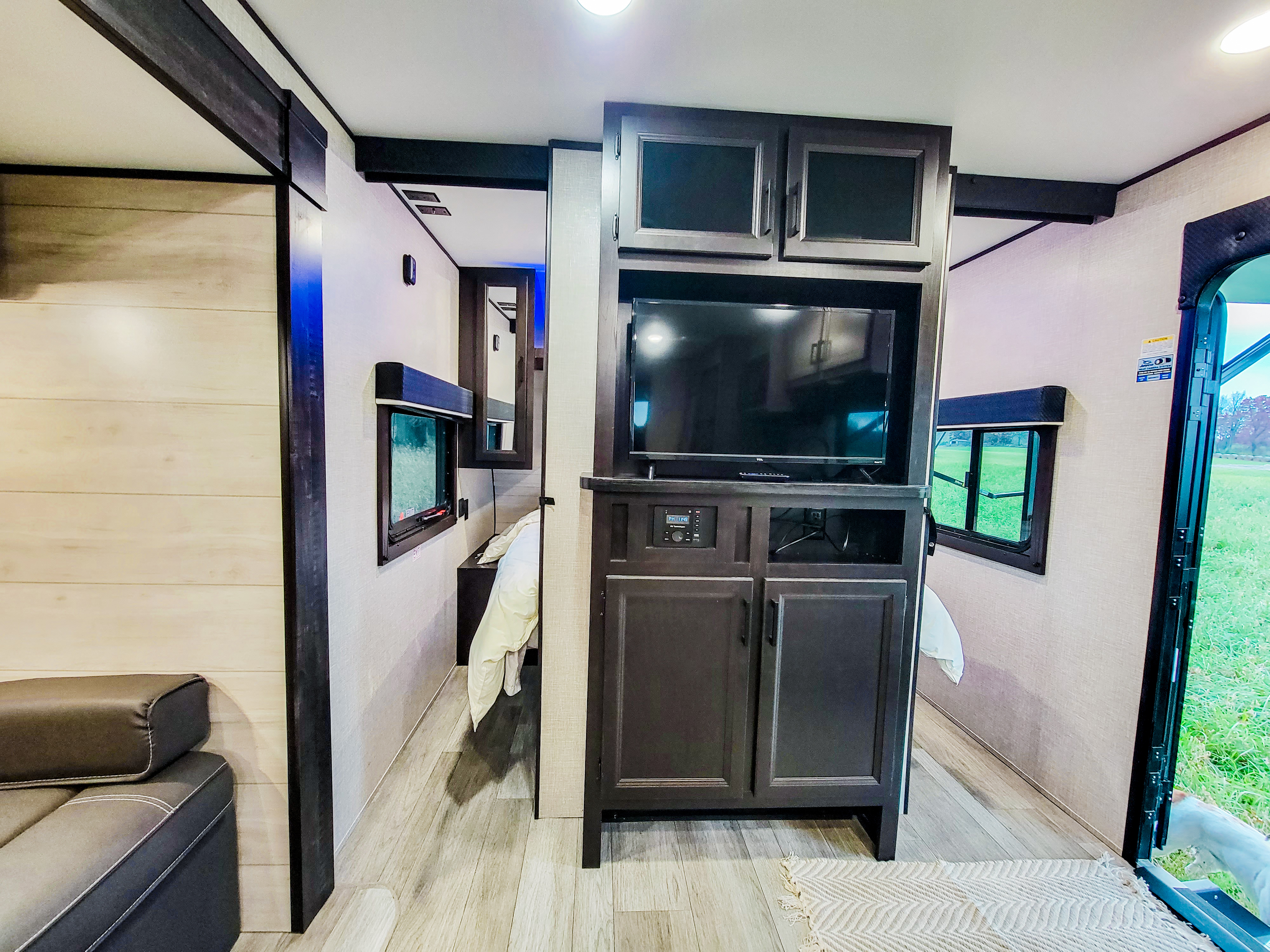 Main living area entertainment center and entrance to master bedroom with queen bed. Jayco Jay Flight SLX 2022