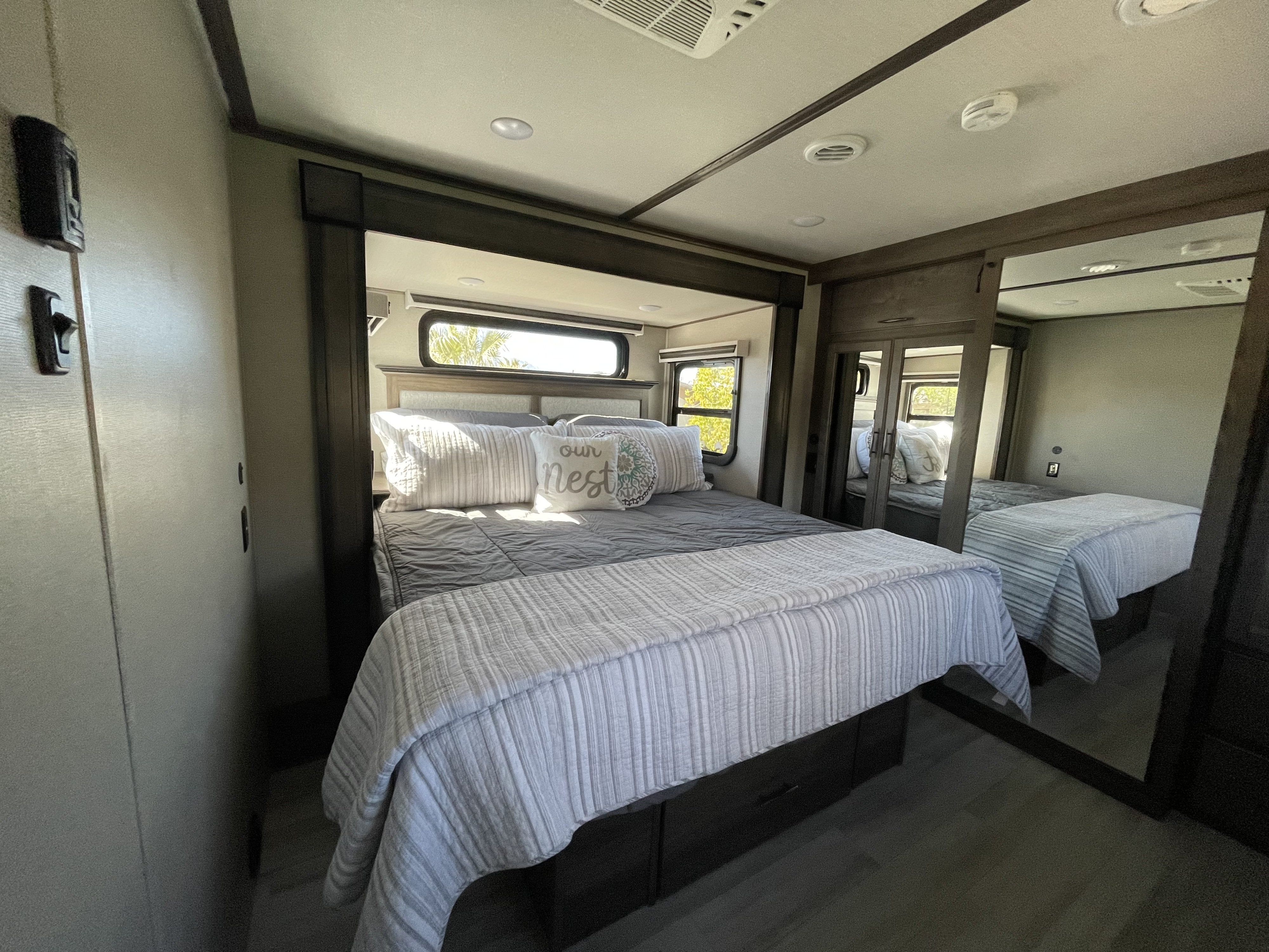 RV rental bedroom: A comfortable queen bed with under-bed storage, mirrored closet, and modern touches for your trip.. Grand Design Solitude 2022
