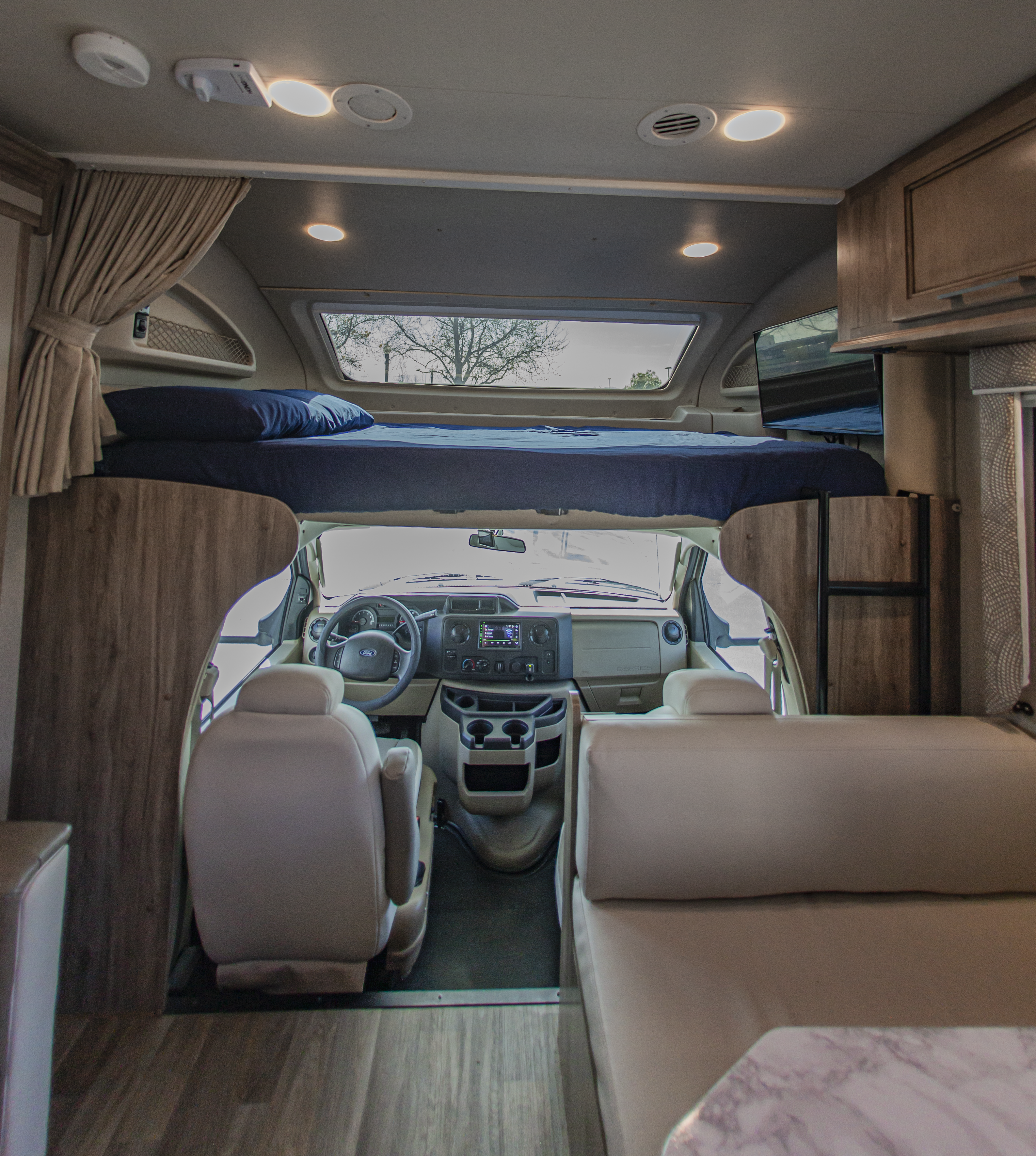 Spacious rv rental interior showing an overhead bed, bright cockpit area, and inviting seating.. Entegra Coach Odyssey 2019