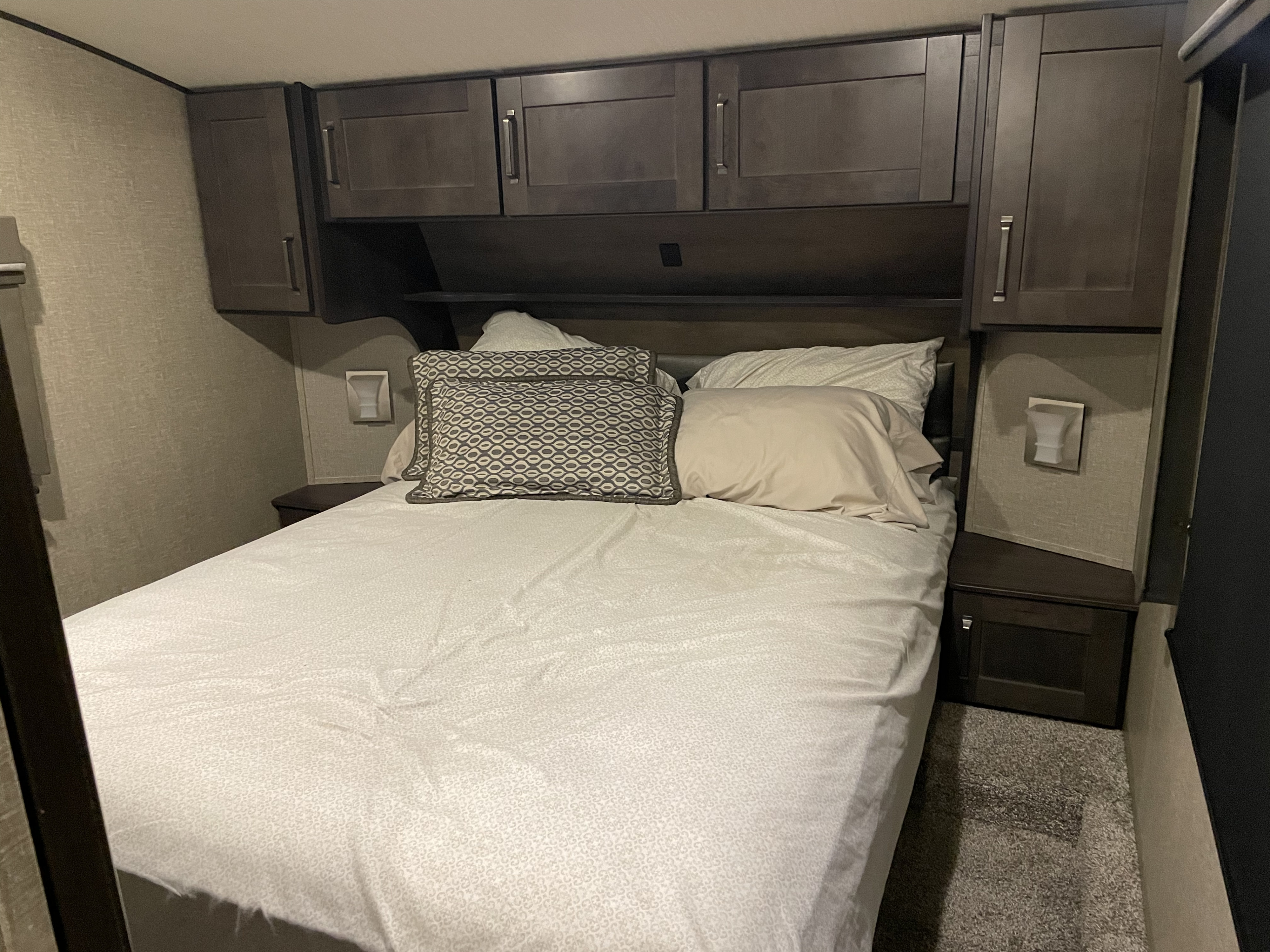 Comfortable RV rental bedroom featuring a full bed, overhead cabinets, and built-in nightstands. Perfect for your next trip.. Grand Design Reflection 2021