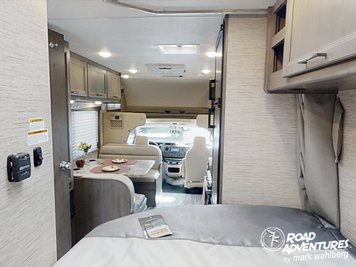 Cozy RV rental interior with a comfy bed, dining dinette, and bright driver's cab visible, offering practical travel comfort.. Thor Motor Coach Four Winds 22E 2024