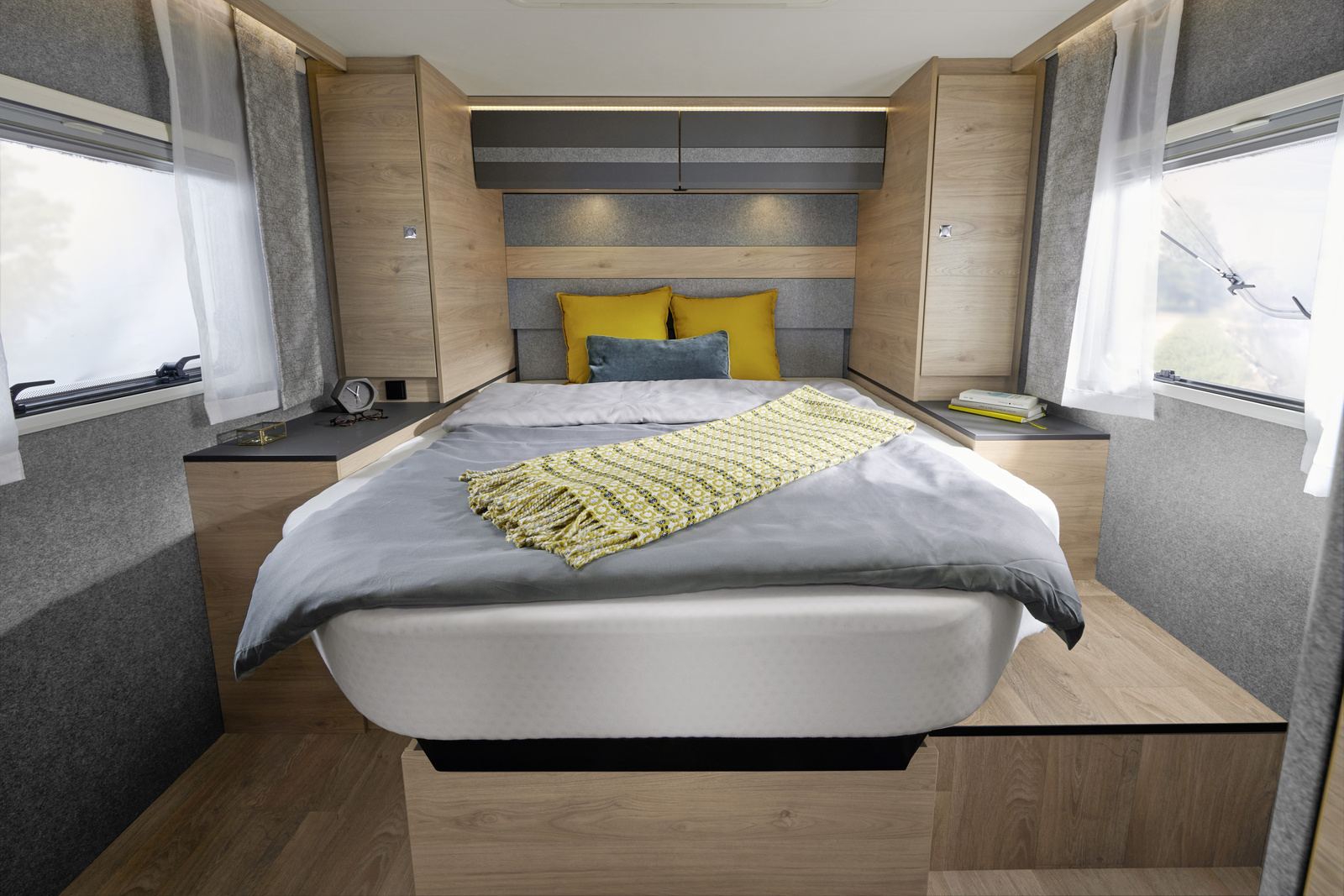 Modern RV rental bedroom with a large bed, nightstands, ambient lighting, and windows for a comfortable journey.. Dethleffs JUST T7052 DBM 2023