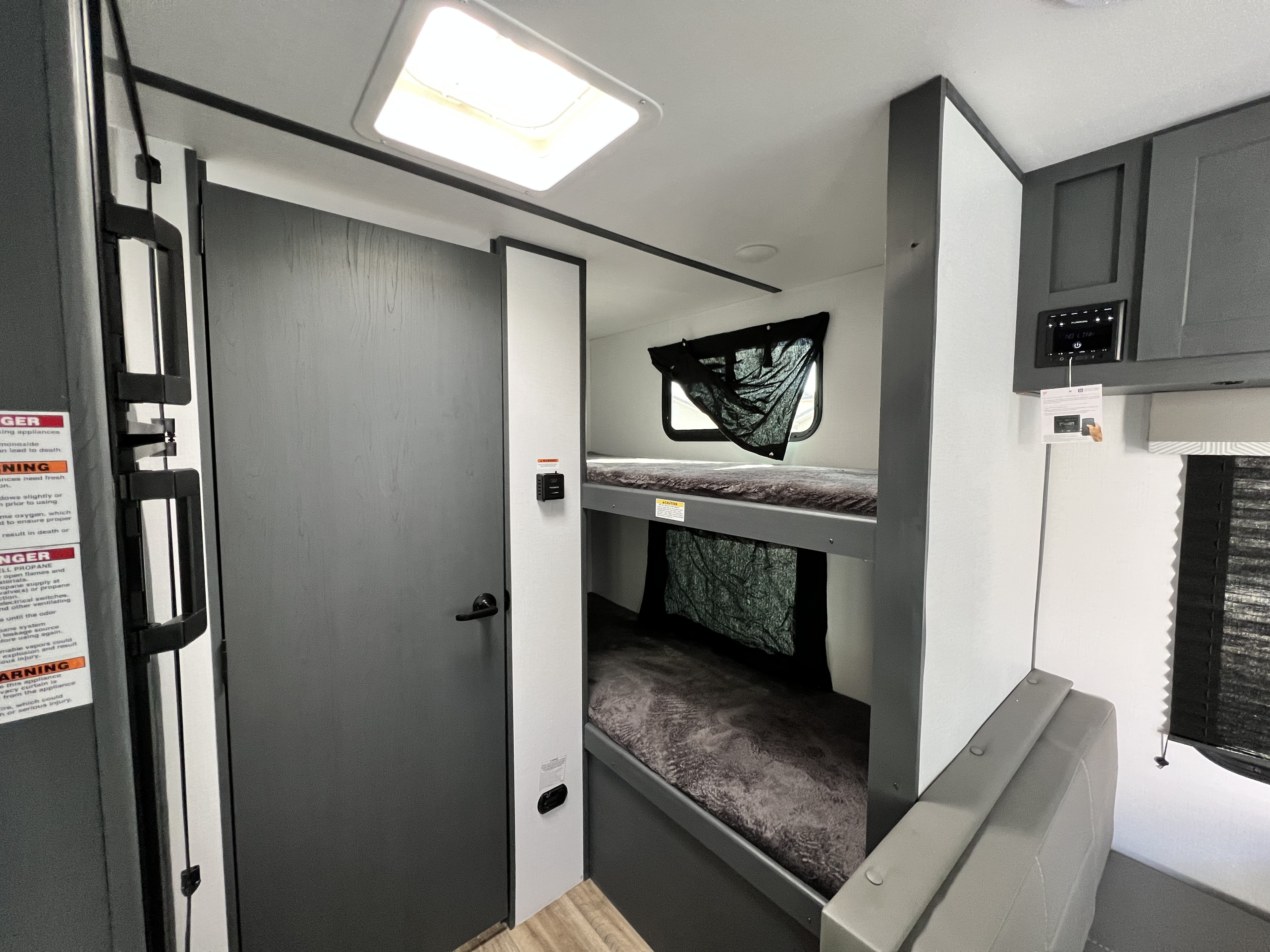 RV rental interior showing bunk beds, a gray door, and a media control panel. Ideal for family adventures.. Keystone RV Bullet Crossfire 2022