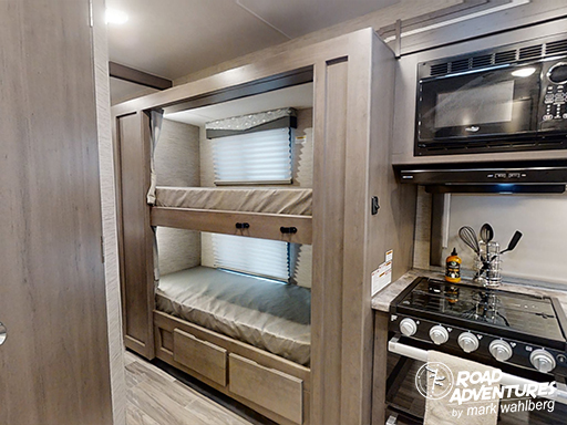 This RV rental interior features bunk beds & a kitchen with a stove/microwave, ideal for road adventures.. Thor Motor Coach Four Winds 2024