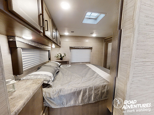 Experience comfort in this modern RV rental bedroom, featuring a neatly made bed, overhead storage, and a skylight.. Thor Motor Coach Four Winds 2024