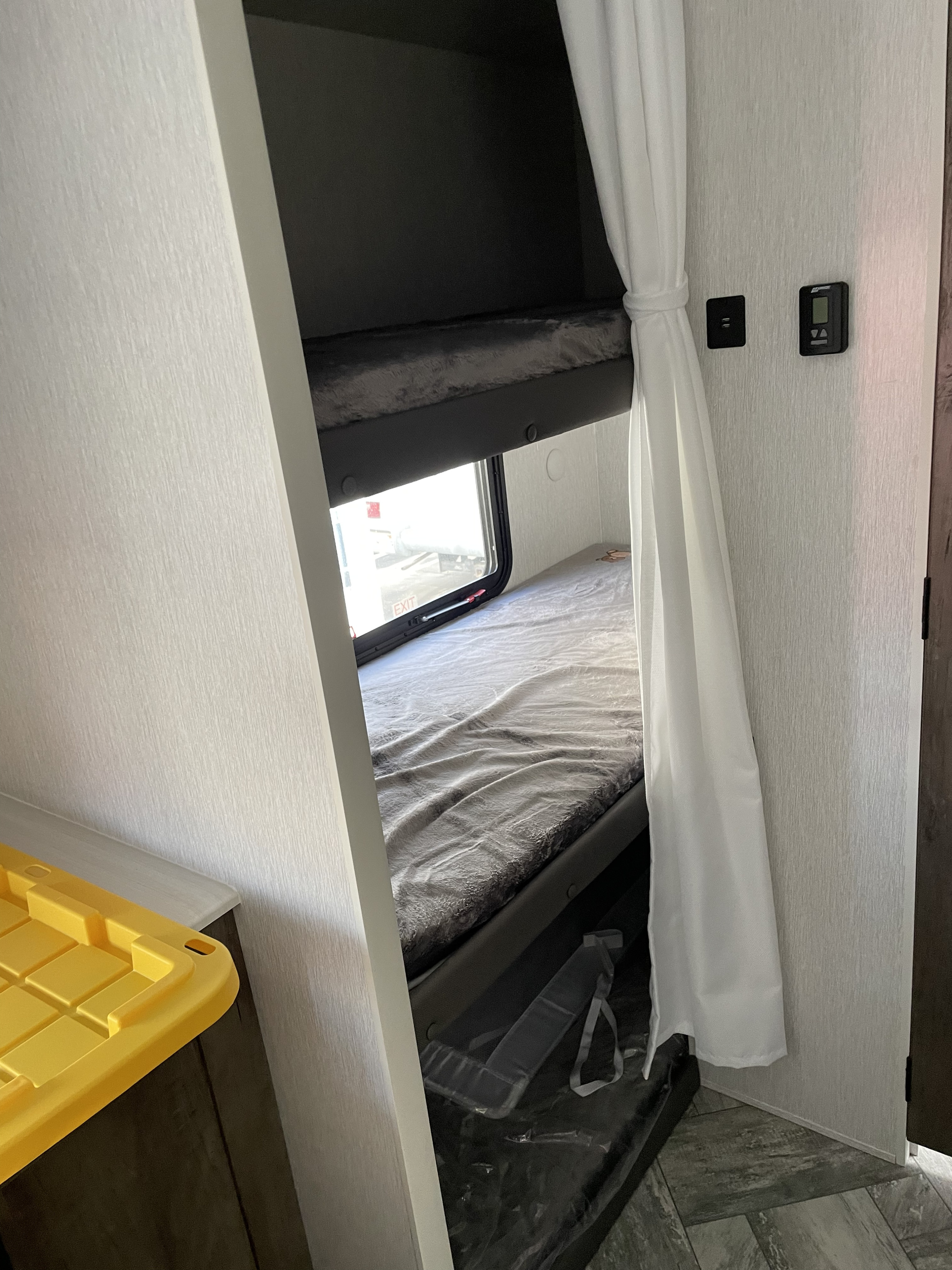 Inside an RV rental: cozy bunk beds with a window, charging port, and climate control panel.. Forest River 2022 Forest River Evo 2022