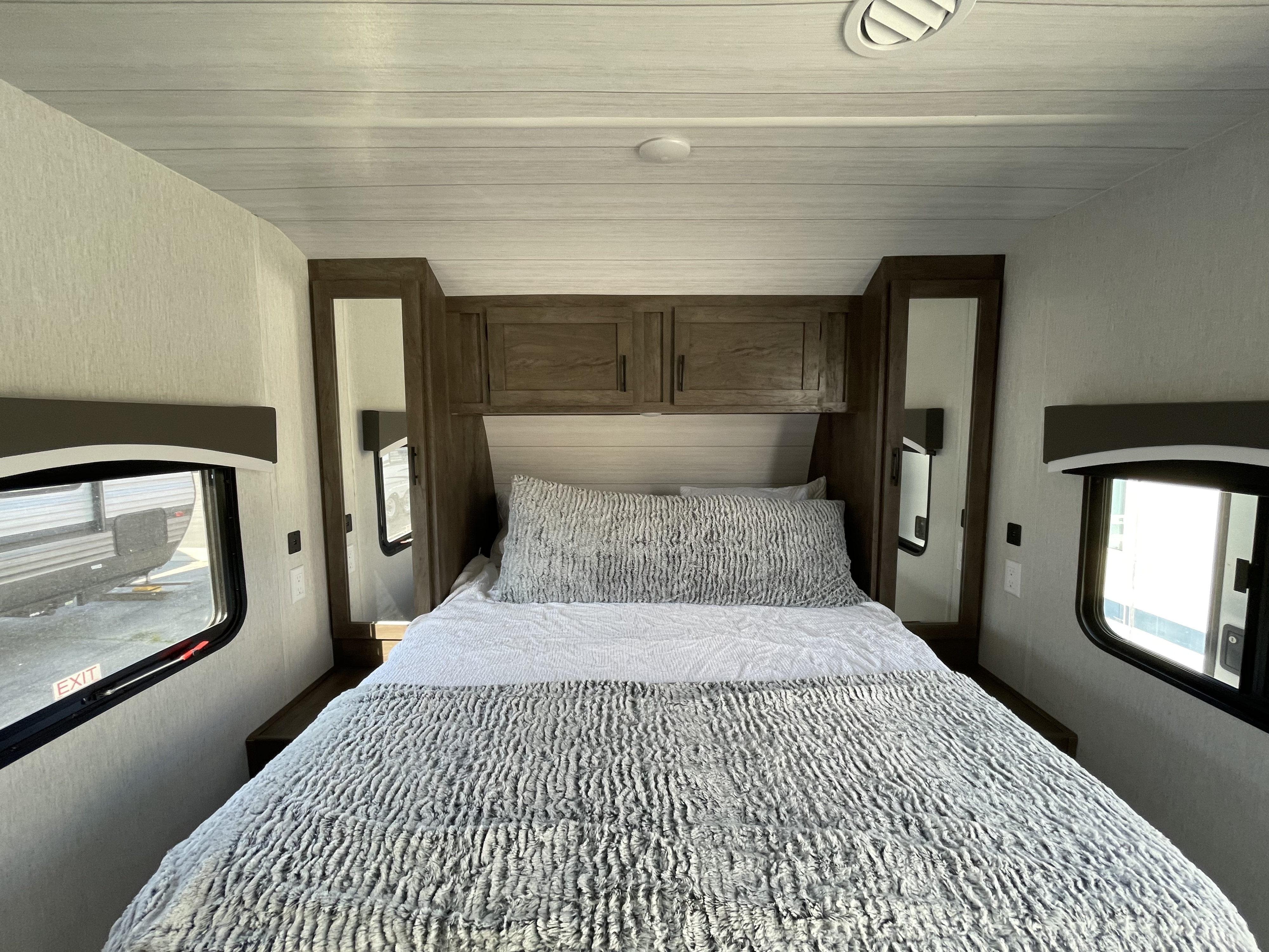 A comfortable RV rental bedroom featuring a cozy bed, overhead storage, and windows for natural light.. Forest River 2022 Forest River Evo 2022