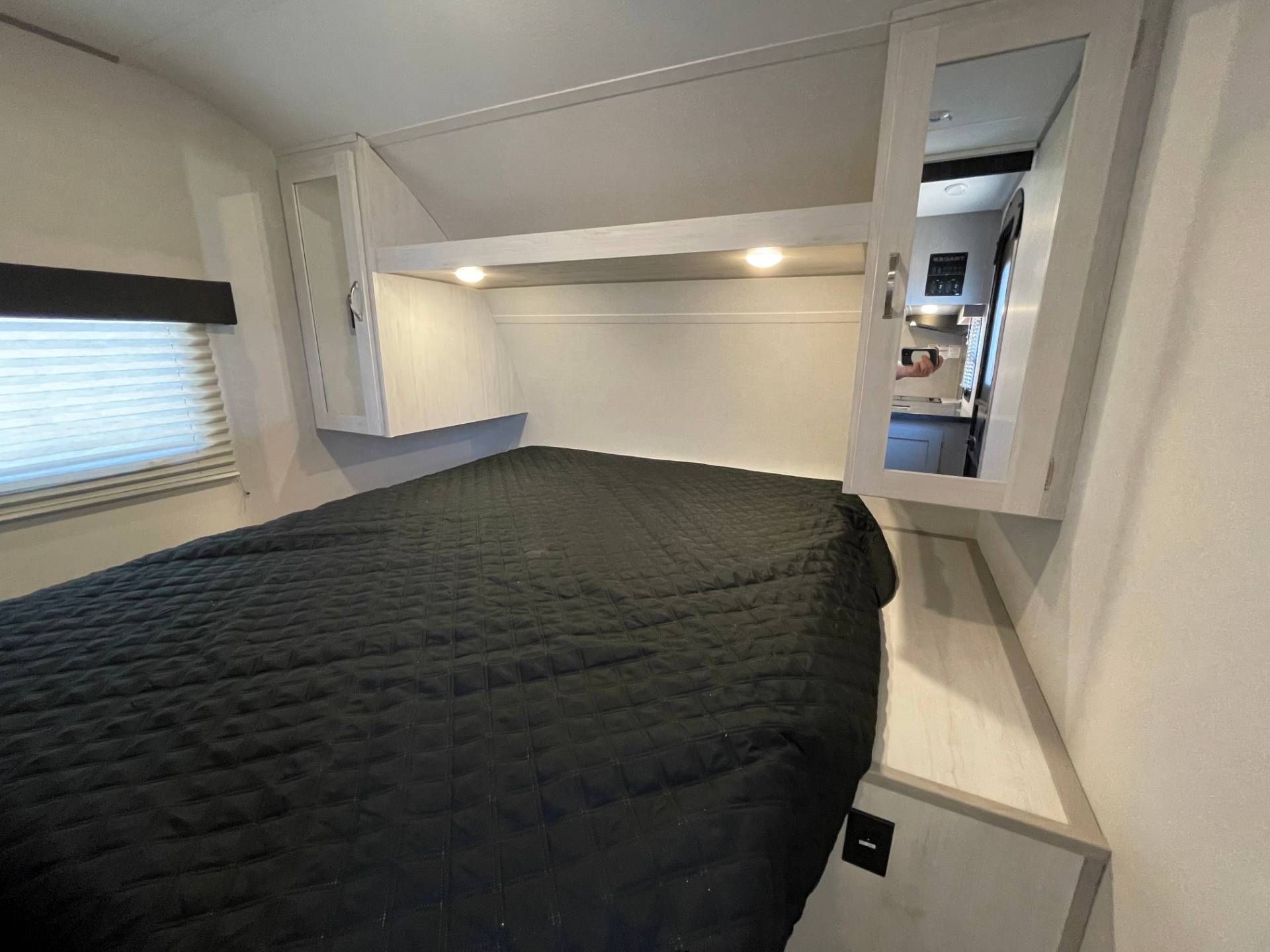 Cozy RV rental bedroom with dark quilted bedspread, overhead cabinets, and soft reading lights.. Forest River Tracer 2022