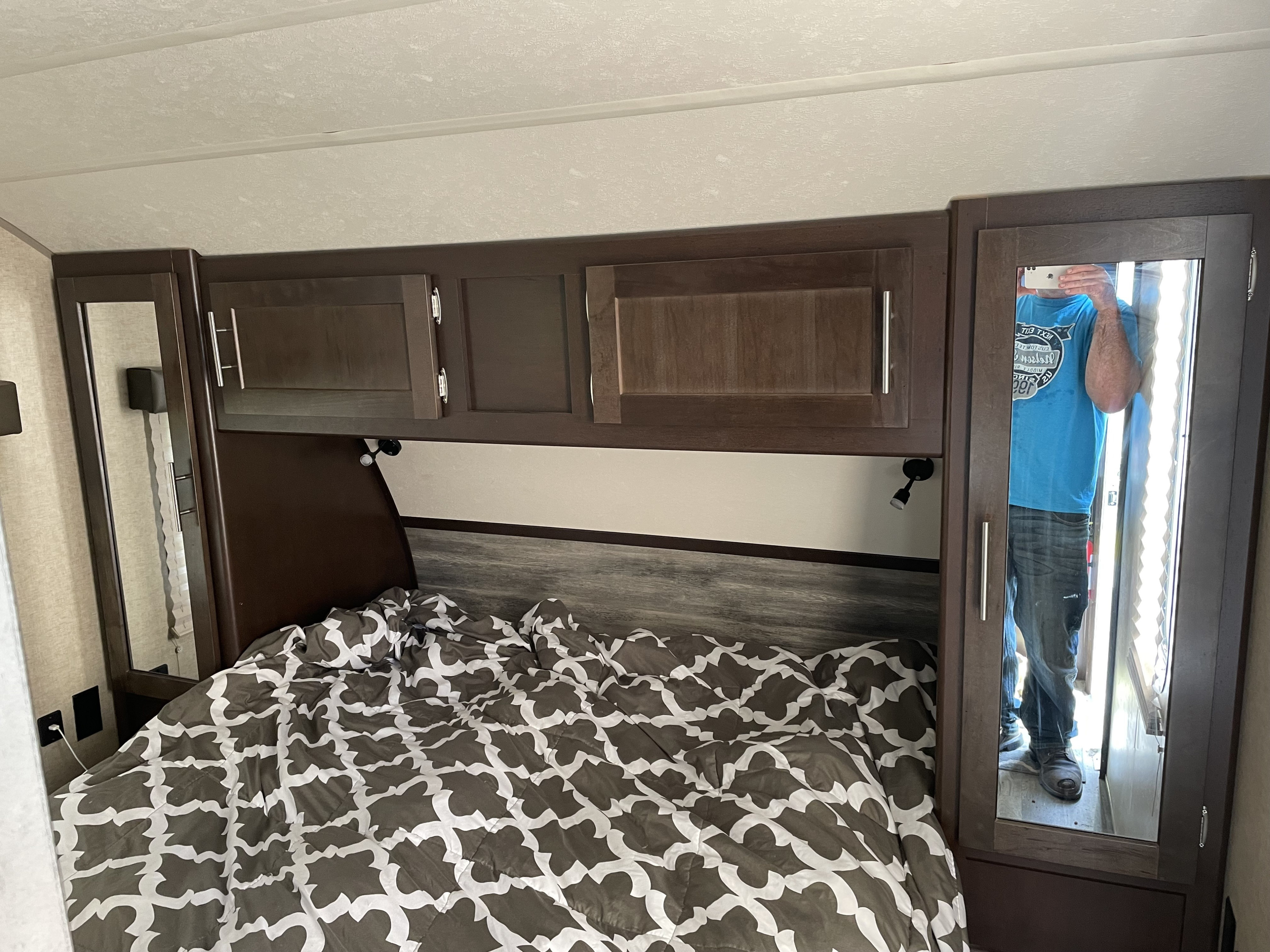 Cozy RV rental bedroom with patterned comforter, overhead storage, and full-length mirrors.. Forest River Cherokee Grey Wolf 2017