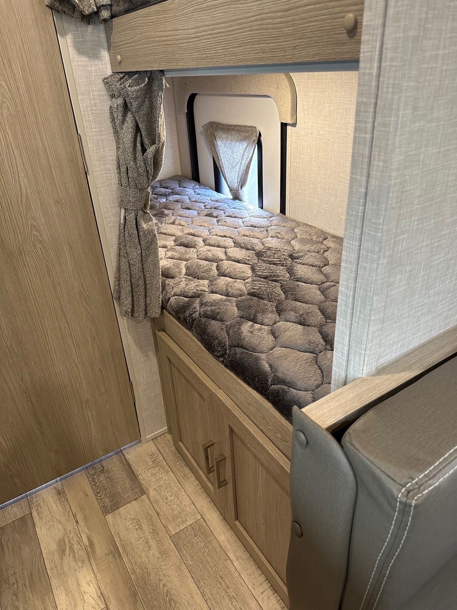 Inside an RV rental: a compact bunk bed with a grey textured blanket, ambient light, and under-bed storage.. Forest River Flagstaff E-Pro 2022