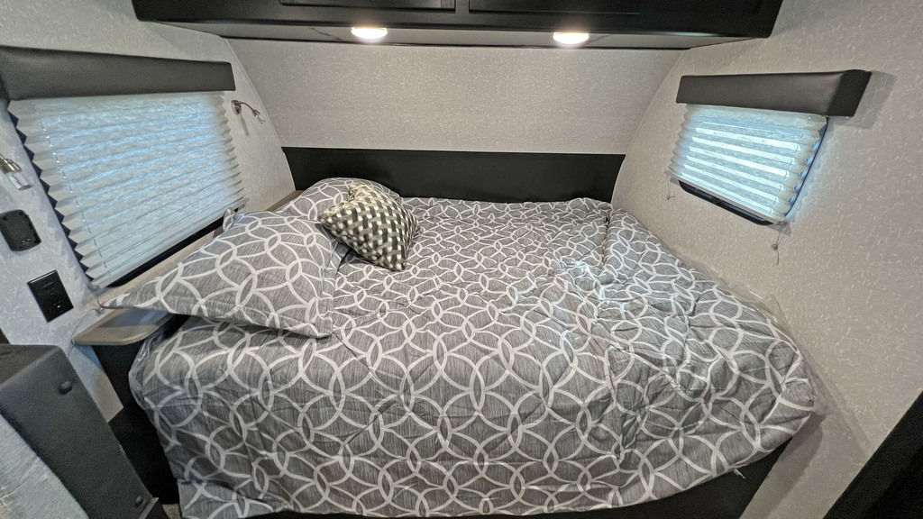Cozy RV rental bedroom with a grey patterned bed, side windows with blinds, and overhead lighting.. Forest River Cherokee Wolf Pup Black Label 2022