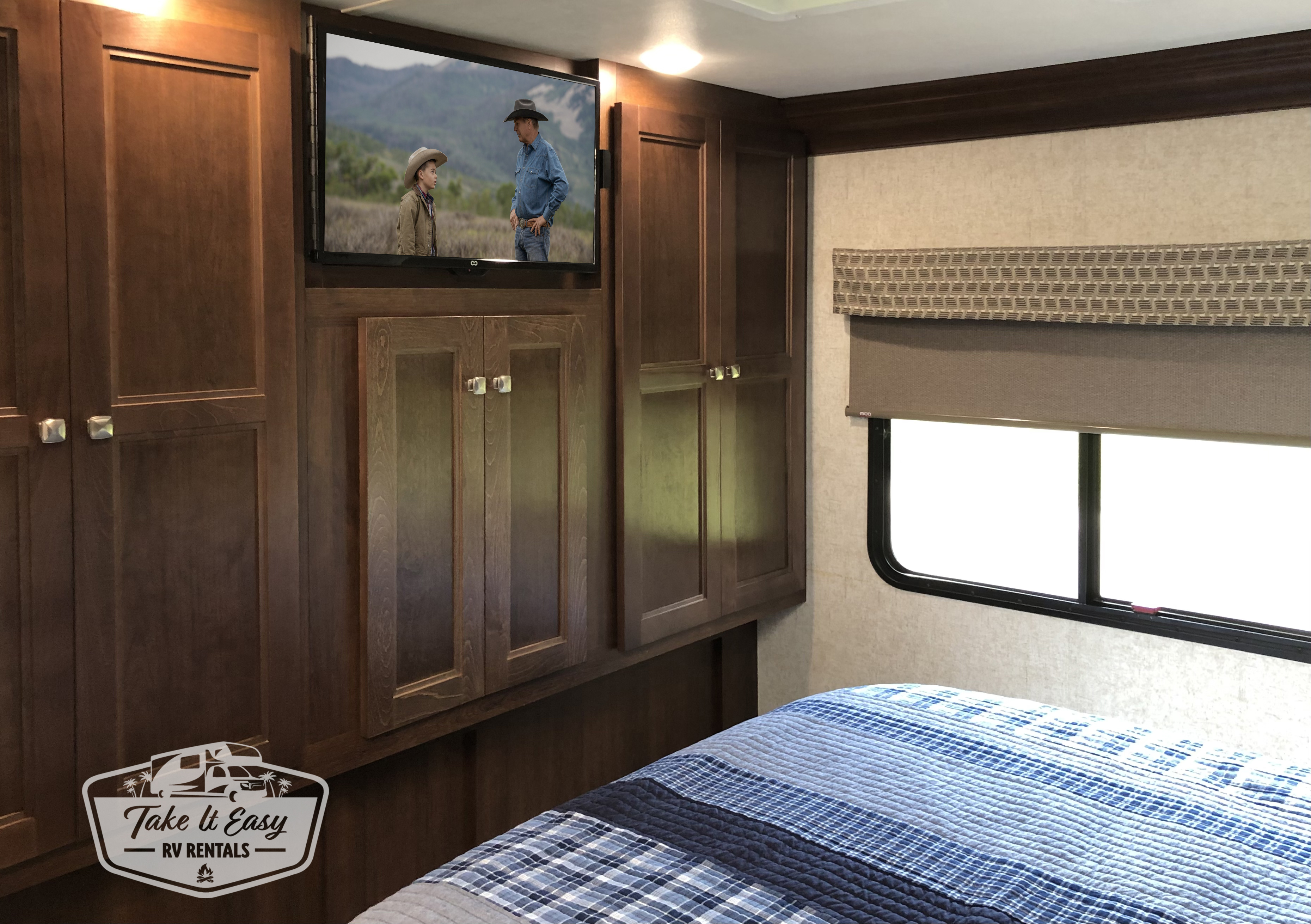 Main bedroom with wardrobe closets, window, and TV with storage space behind.. Forest River Sunseeker 2019