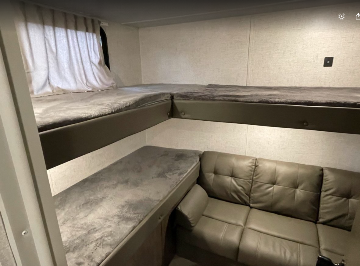 RV rental interior: L-shaped upper bunk beds and a lower sofa. Efficient sleeping & lounging space.. Forest River Wildwood X-Lite 2021