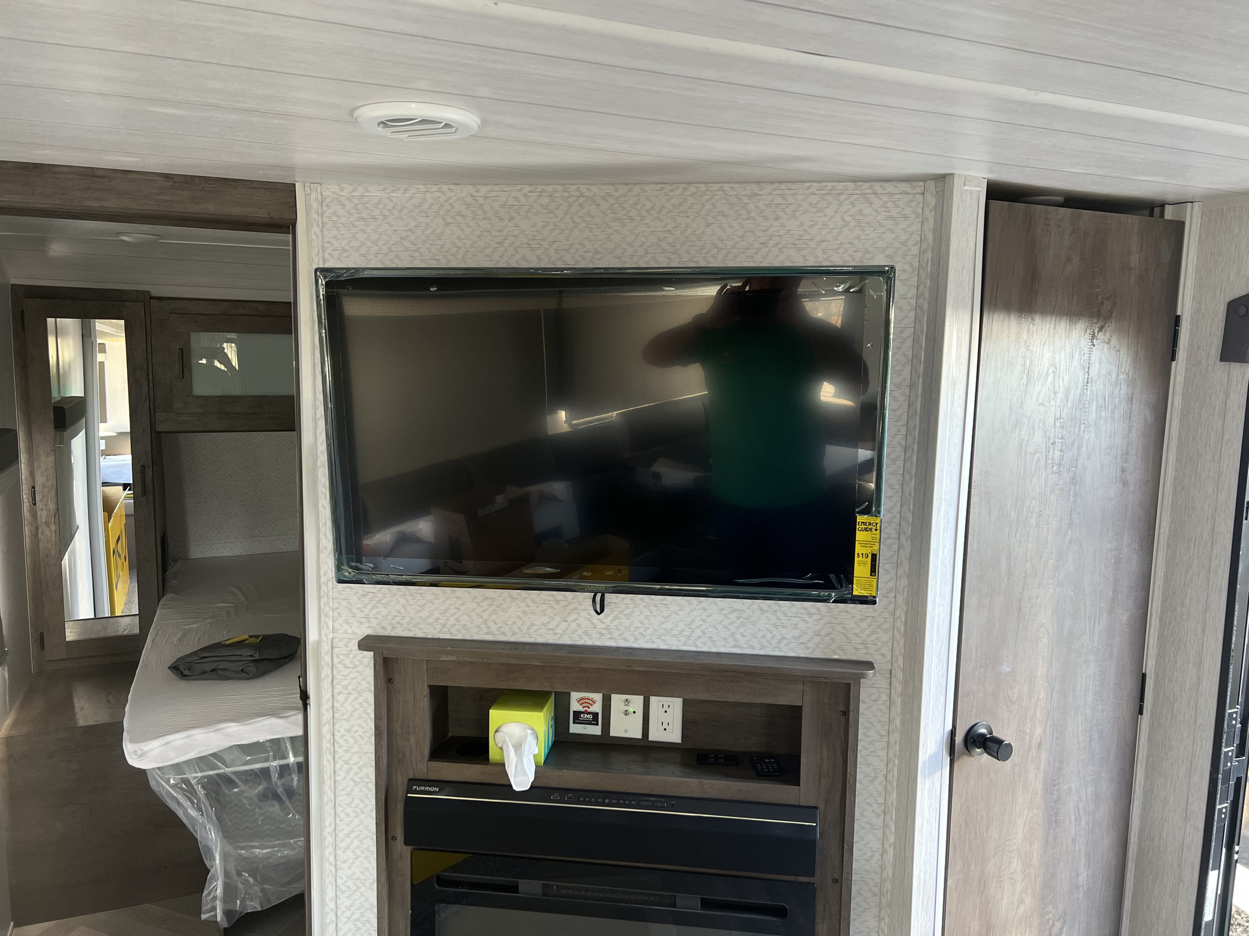 Modern RV rental living space featuring a large TV, entertainment console, and view into a new, clean bedroom.. Forest River Wildwood 2022