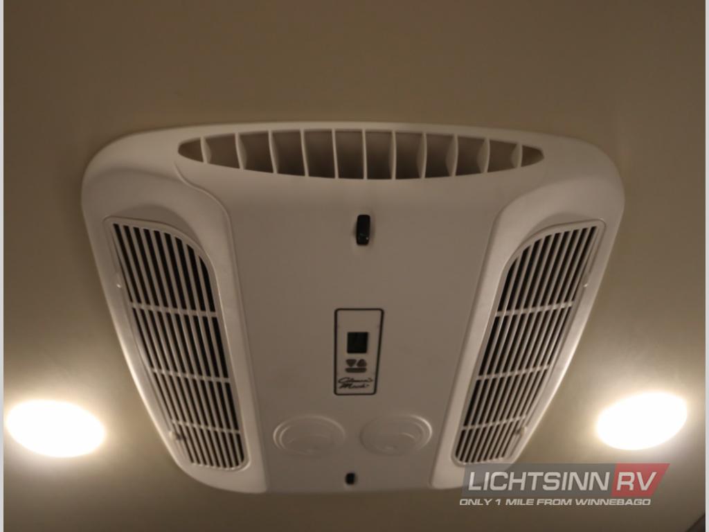 Overhead view inside an RV rental, showcasing the central air conditioning unit with vents and two bright ceiling lights for comfort.. Winnebago Revel 2023