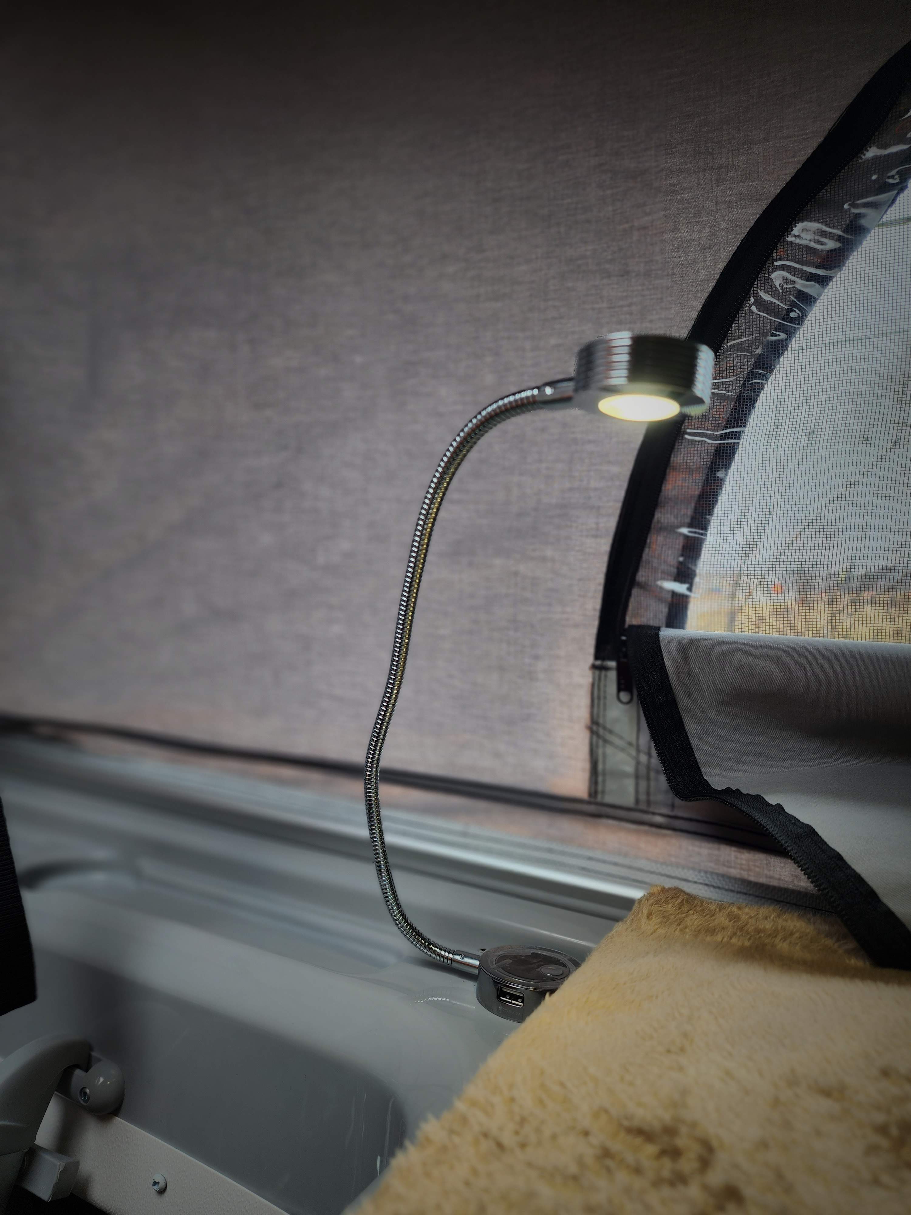 Modern RV rental interior: flexible LED lamp with USB ports illuminates a cozy sleeping area and screen window.. Thor Scope 2023