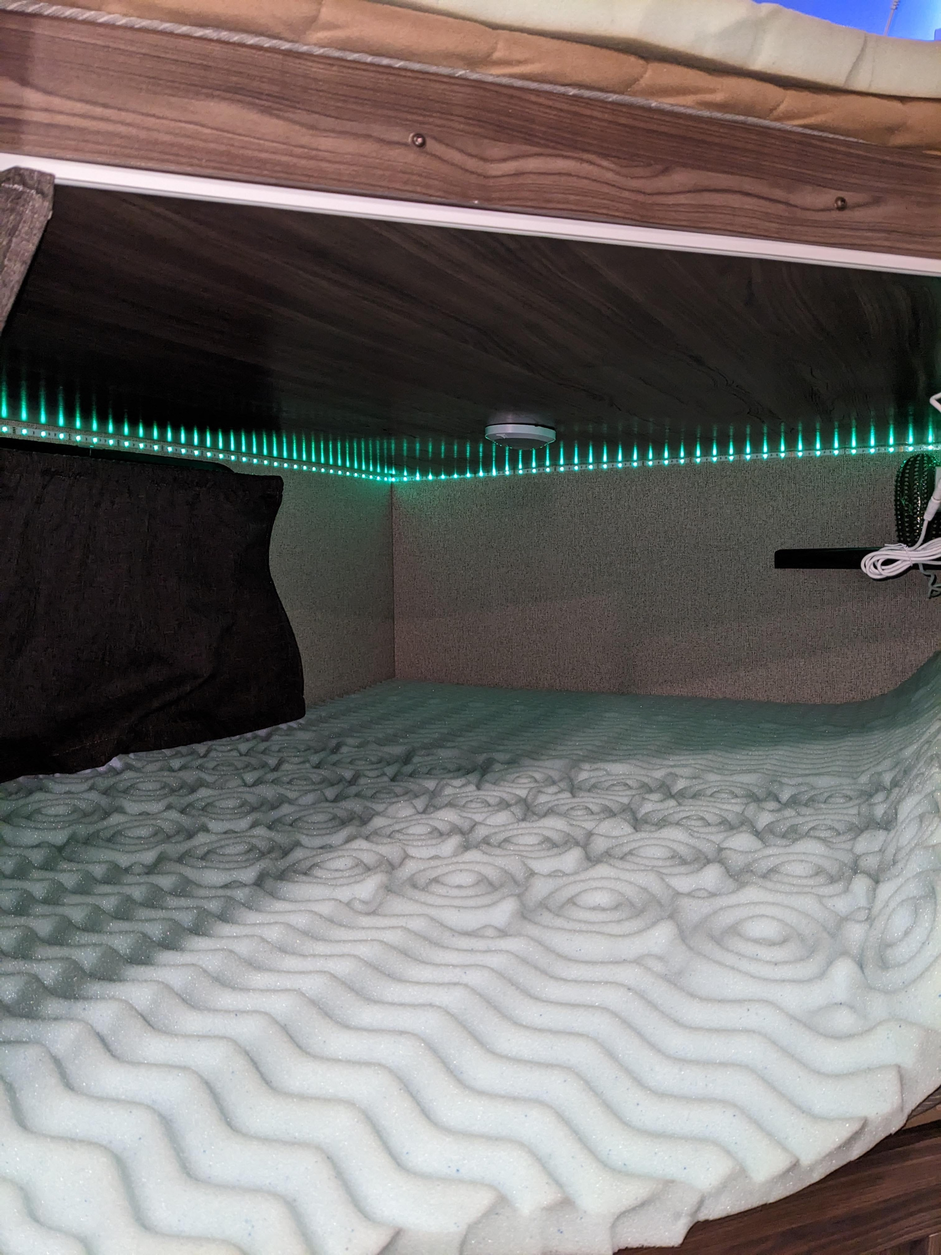 RV rental bunk bed: lit by green LEDs, featuring a textured foam mattress and a pillow for cozy nights.. Coachmen Apex LE 2018