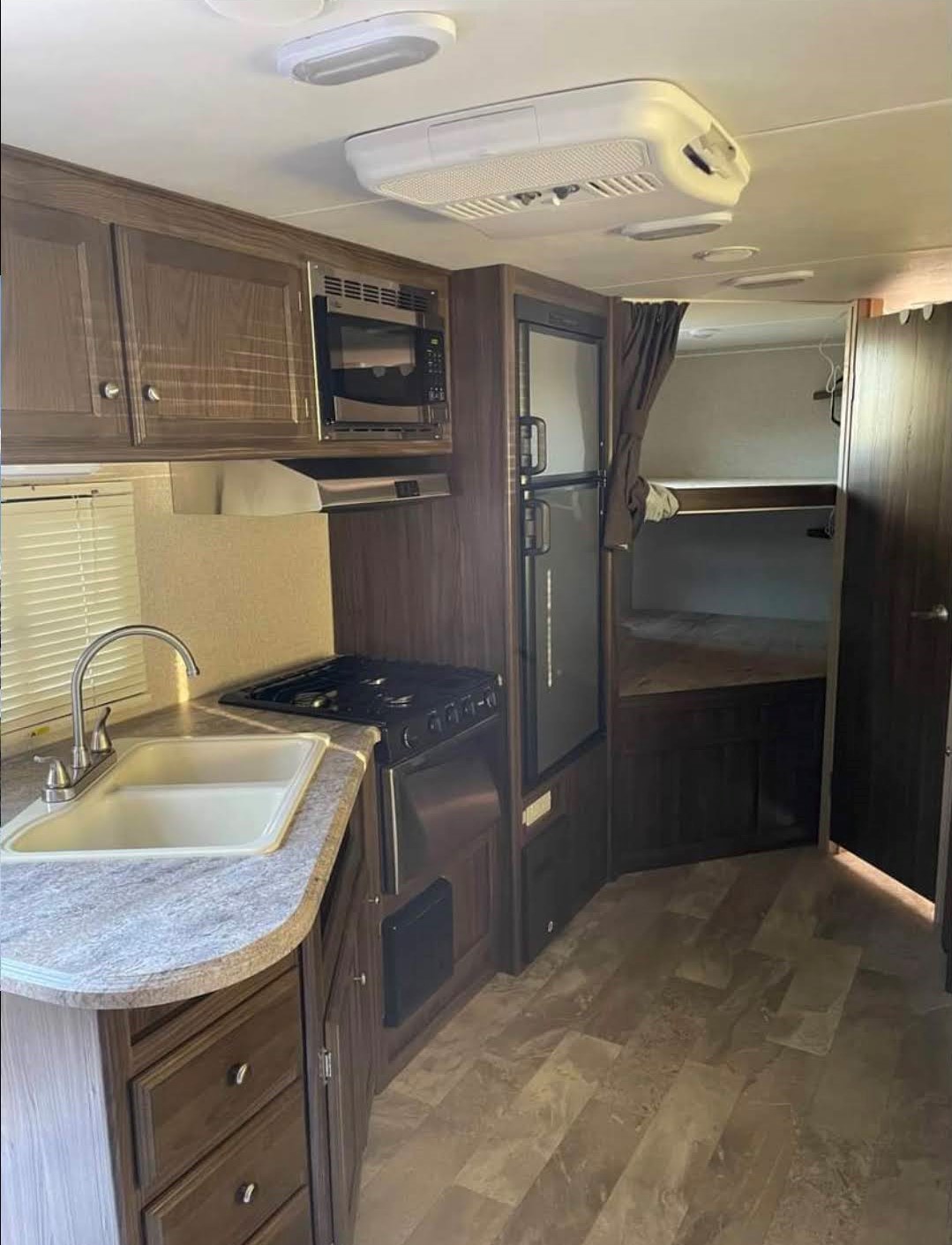 RV rental interior: kitchen with microwave, stove, sink, fridge; plus bunk beds. Ideal for adventure trips.. Coachmen Apex LE 2018