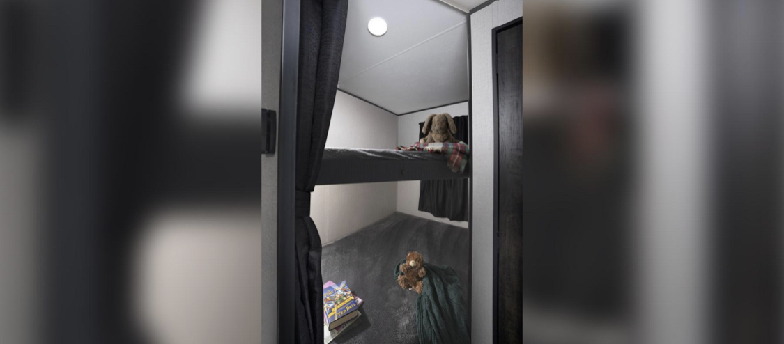 Experience comfort in our rv rental: a compact, family-friendly sleeping area featuring cozy bunk beds with privacy curtains.. Highland Ridge RV Open Range 2022