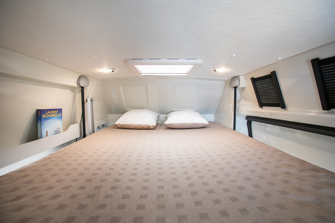 Interior: Cozy RV rental bedroom features a large bed, pillows, overhead skylight, and reading lights.. Font Vendome Horizon H307 2023