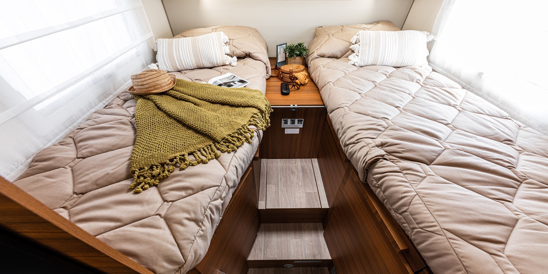 Cozy RV rental sleeping area with two comfy beds, a shared nightstand, and steps. Ideal for compact travel.. Elnagh Baron 65 2023