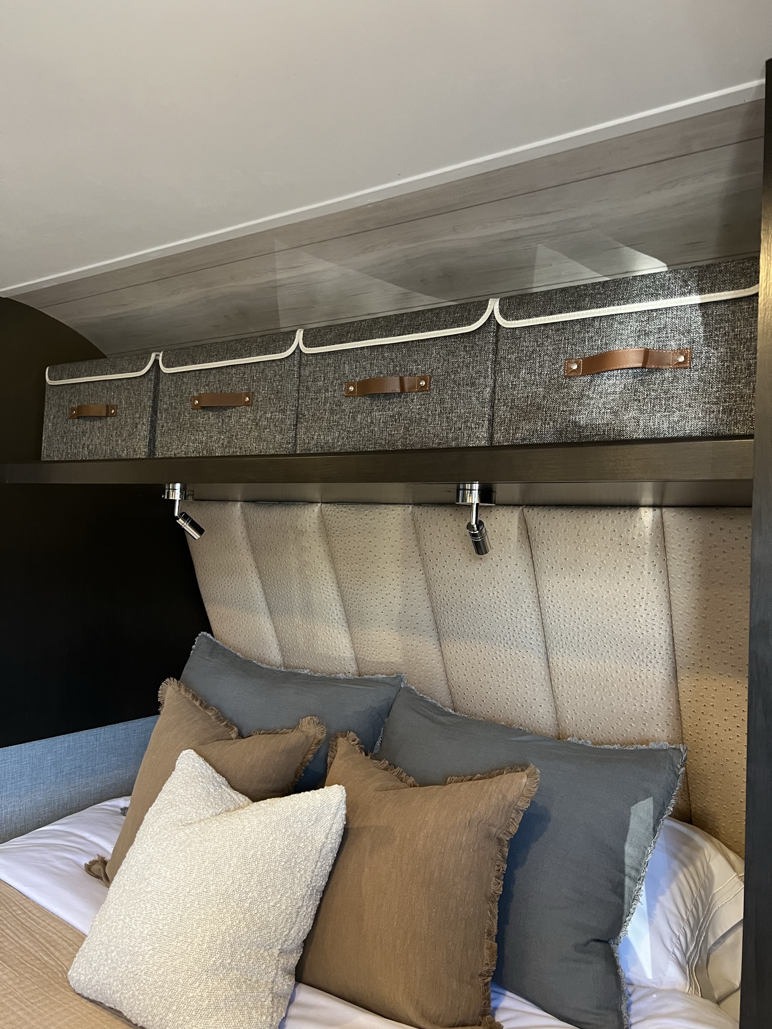 Comfortable RV rental bedroom featuring a padded headboard, cozy pillows, and overhead storage bins with reading lights.. Jayco Featherlight SLX8 2022