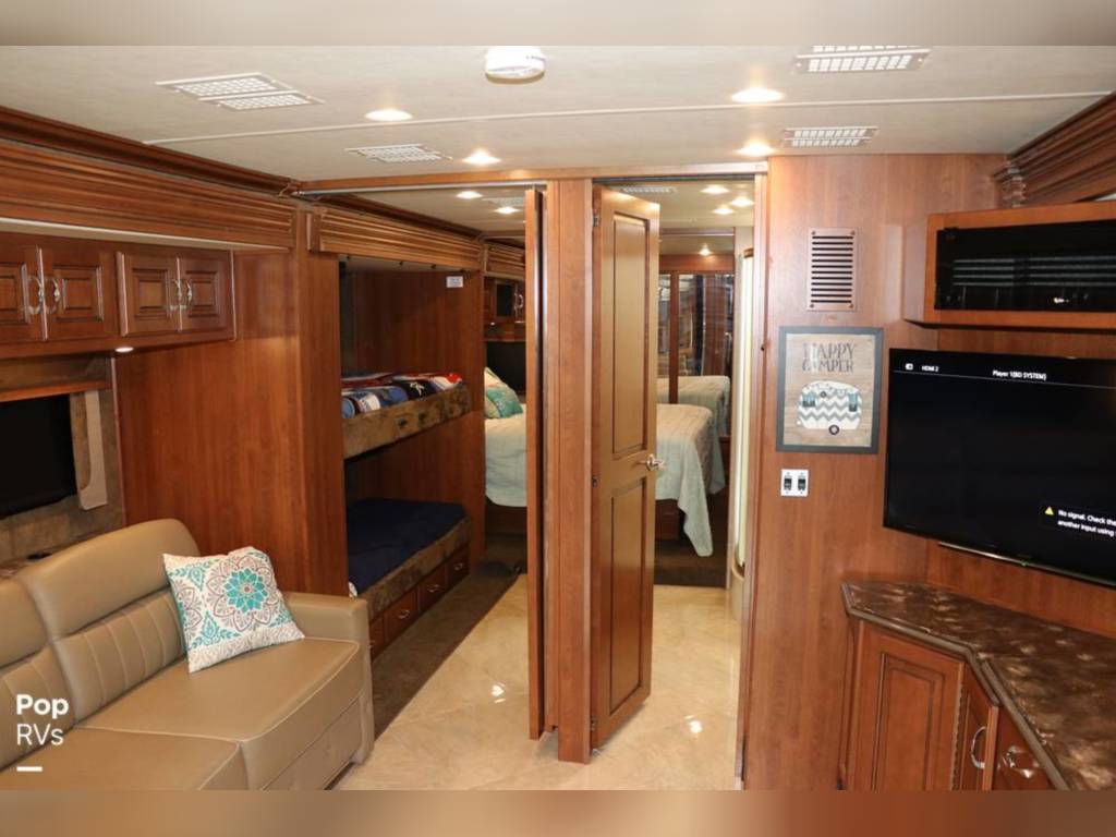 Spacious RV rental interior with wood cabinetry, comfy sofa, bunk beds, and a private bedroom. Ideal for family trips.. Fleetwood Discovery 2011