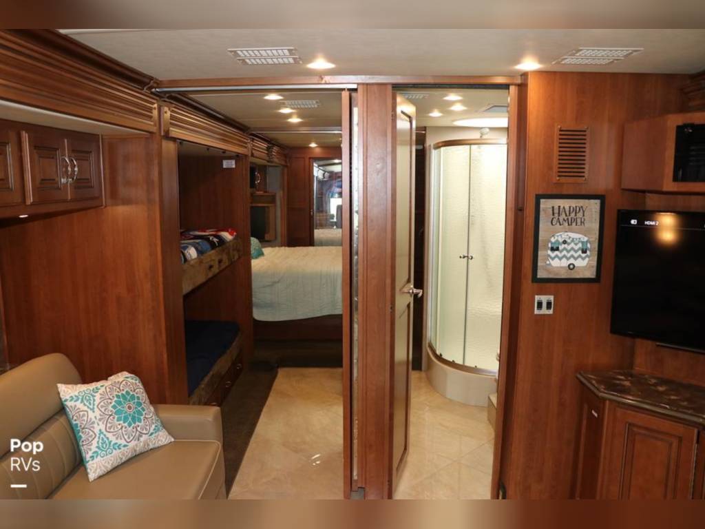 Cozy RV rental interior with bunk beds, master bed, and a curved shower. Ideal family living space.. Fleetwood Discovery 2011