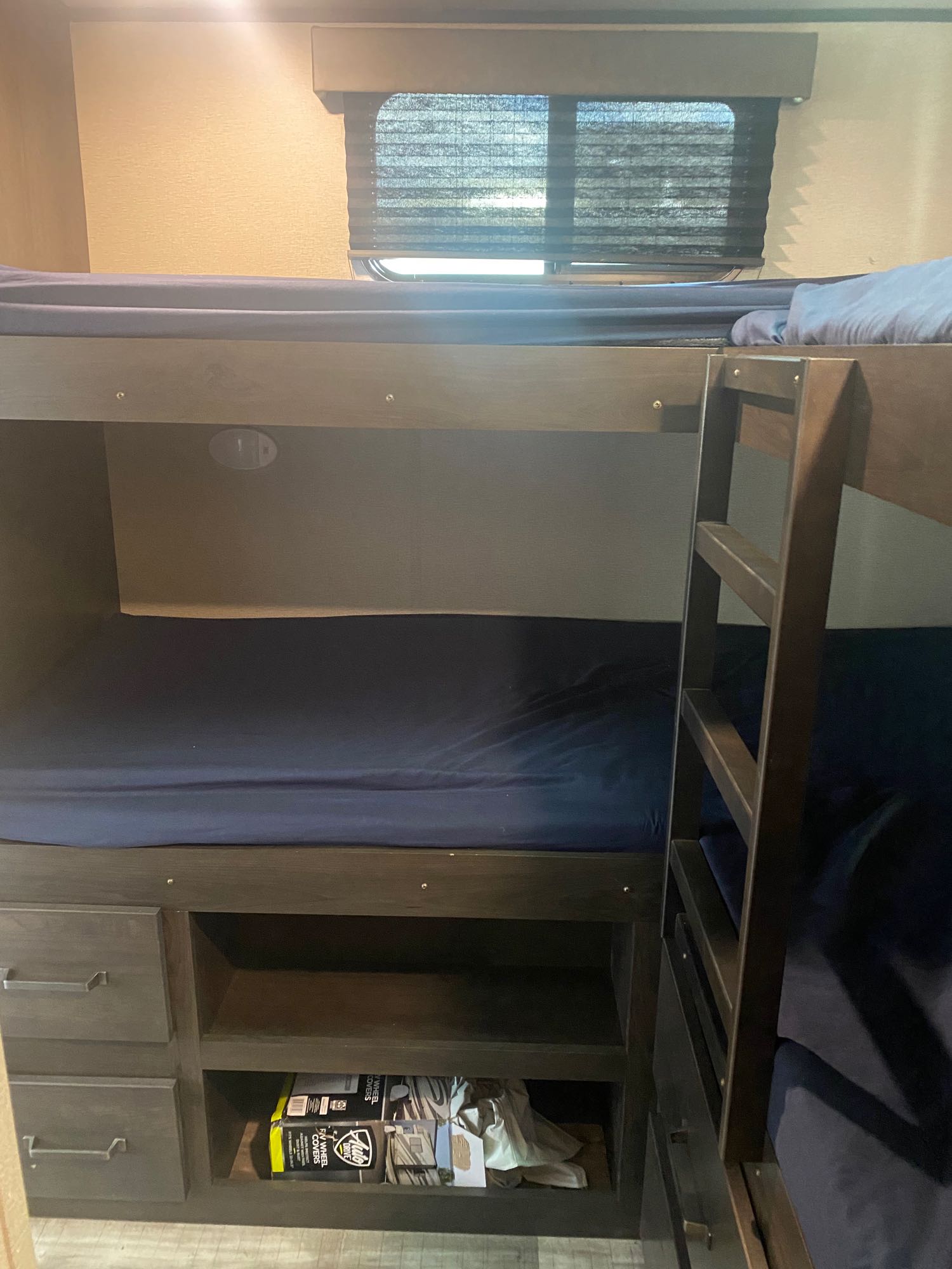 Comfy RV rental bunk beds with dark wood, ample storage & window view inside the travel trailer.. Grand Design Transcend 2022