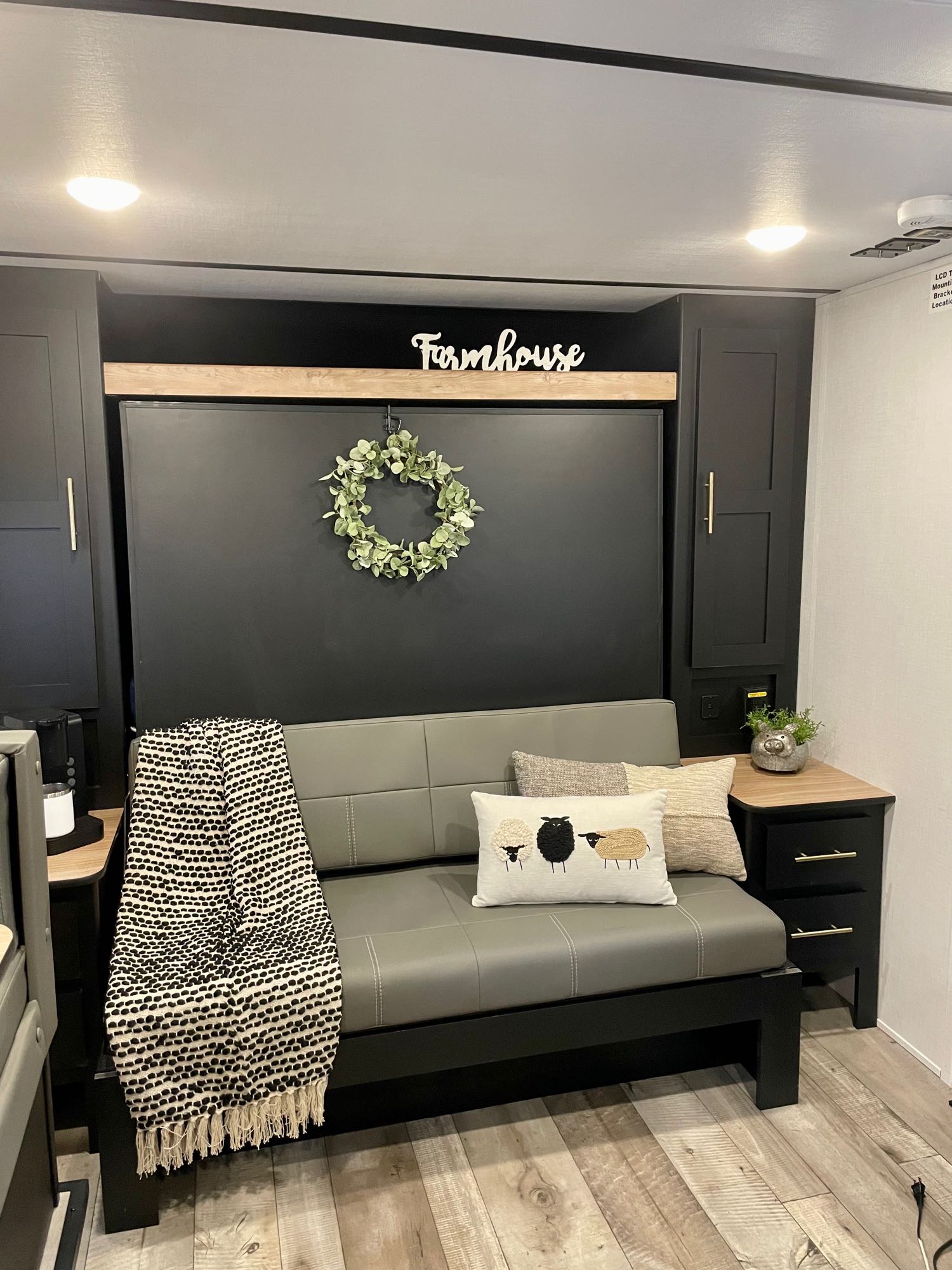 Modern farmhouse RV rental interior: gray sofa, black accent wall with "Farmhouse" sign, and cozy decor.. Keystone RV Springdale Mini 1810BH 2023