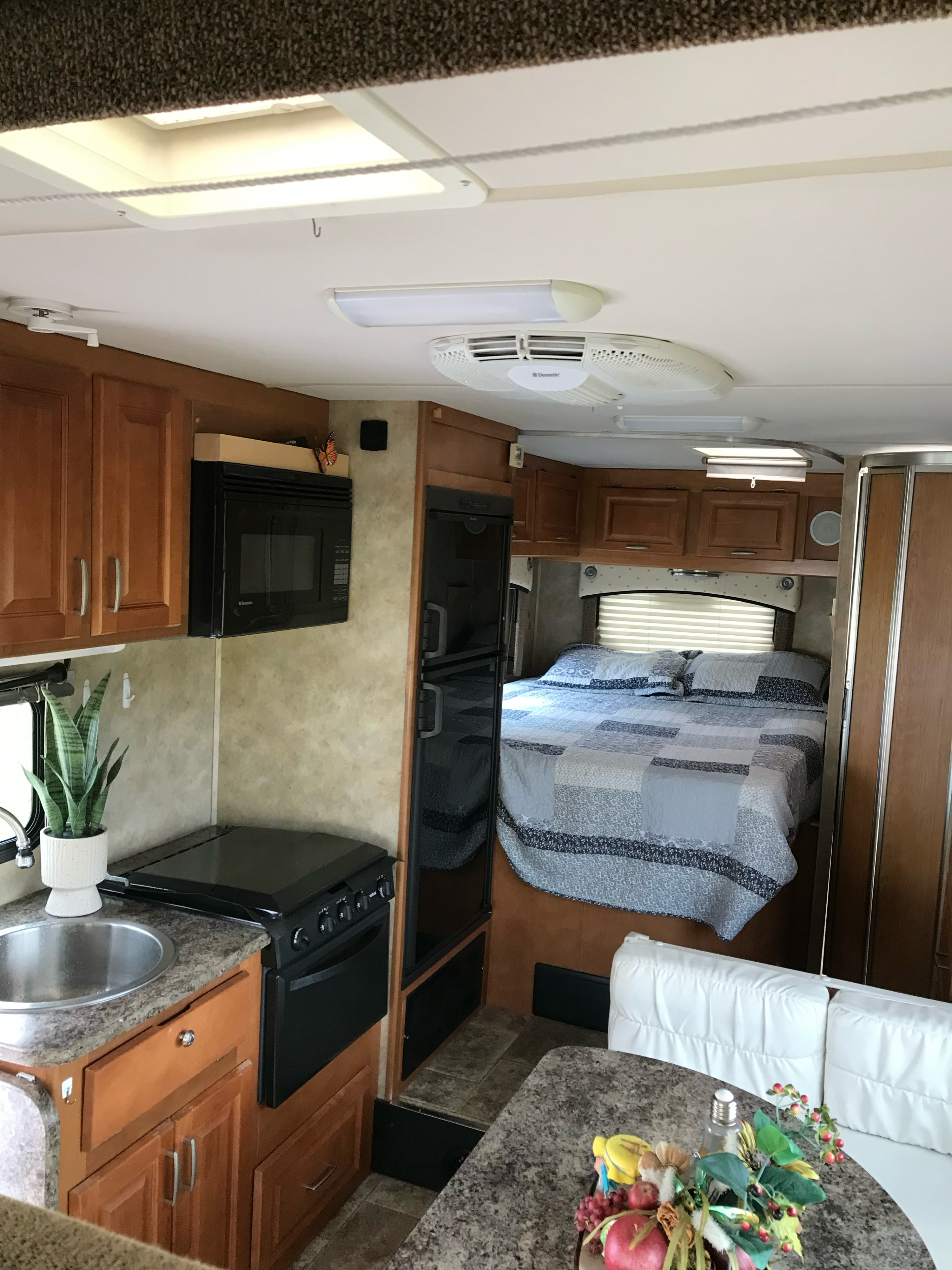 Inside an RV rental: a full kitchen, bedroom with quilted bed, and dining area. All set for your next road trip.. Ford CTV 2011