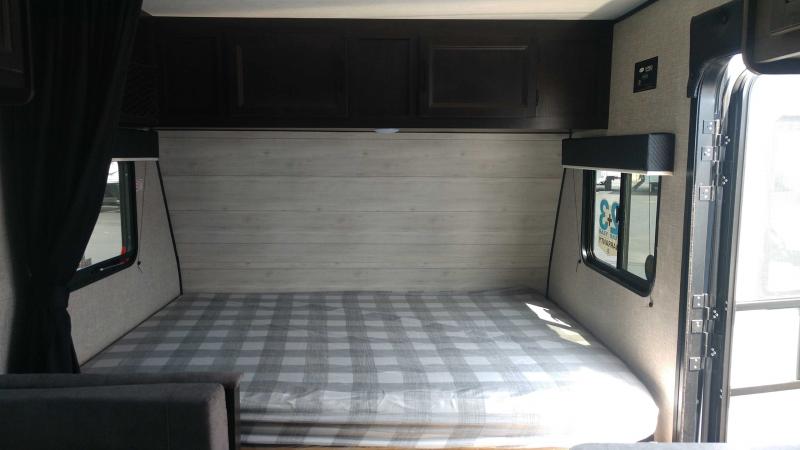 Inside this RV rental, find a comfortable bed with plaid bedding, overhead cabinets, and windows on both sides.. Jayco Jay Flight SLX 2022