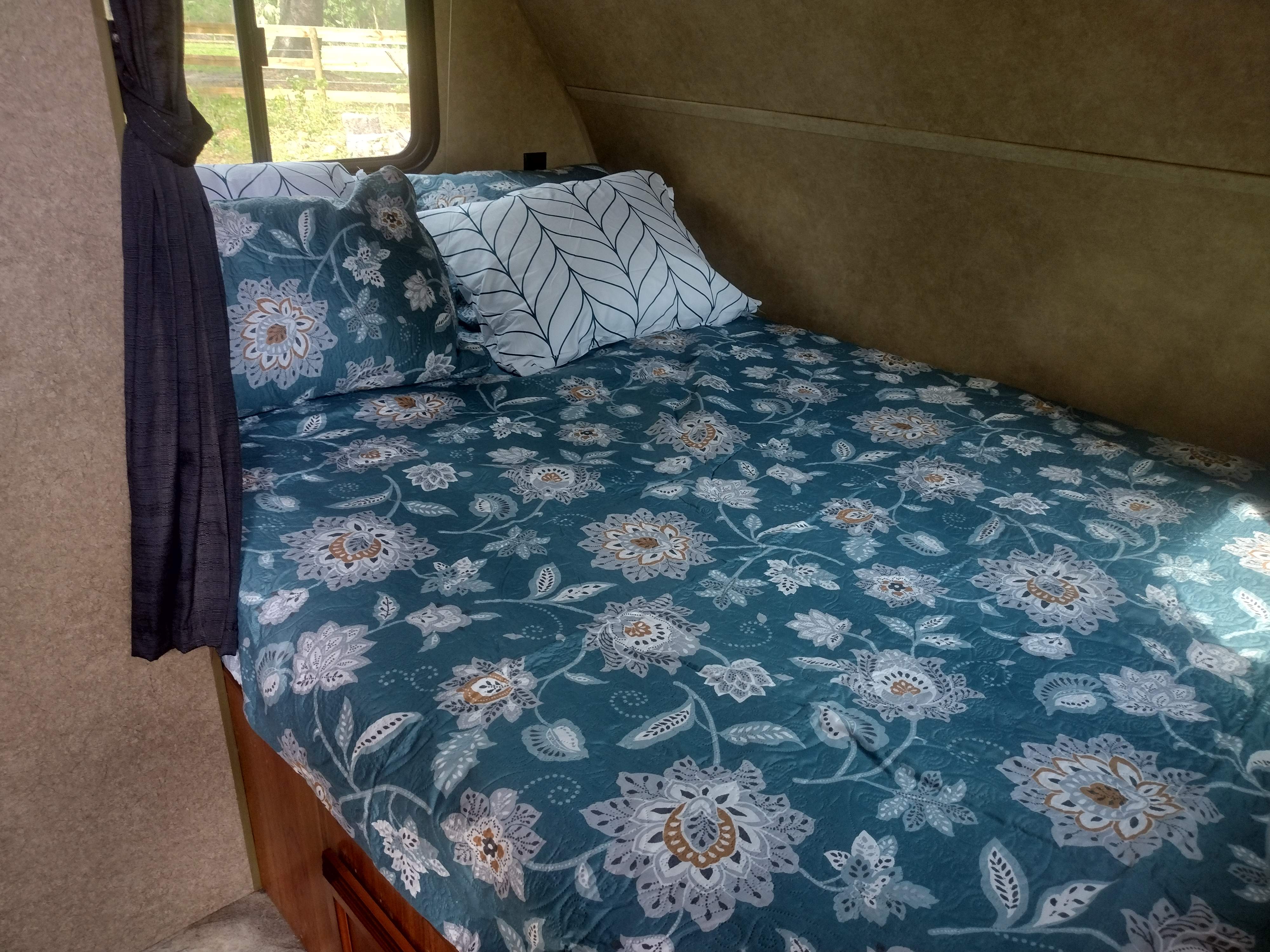 Cozy RV rental bedroom with floral bedding and patterned pillows, offering a comfortable space with natural light.. Starcraft AR-One 2015