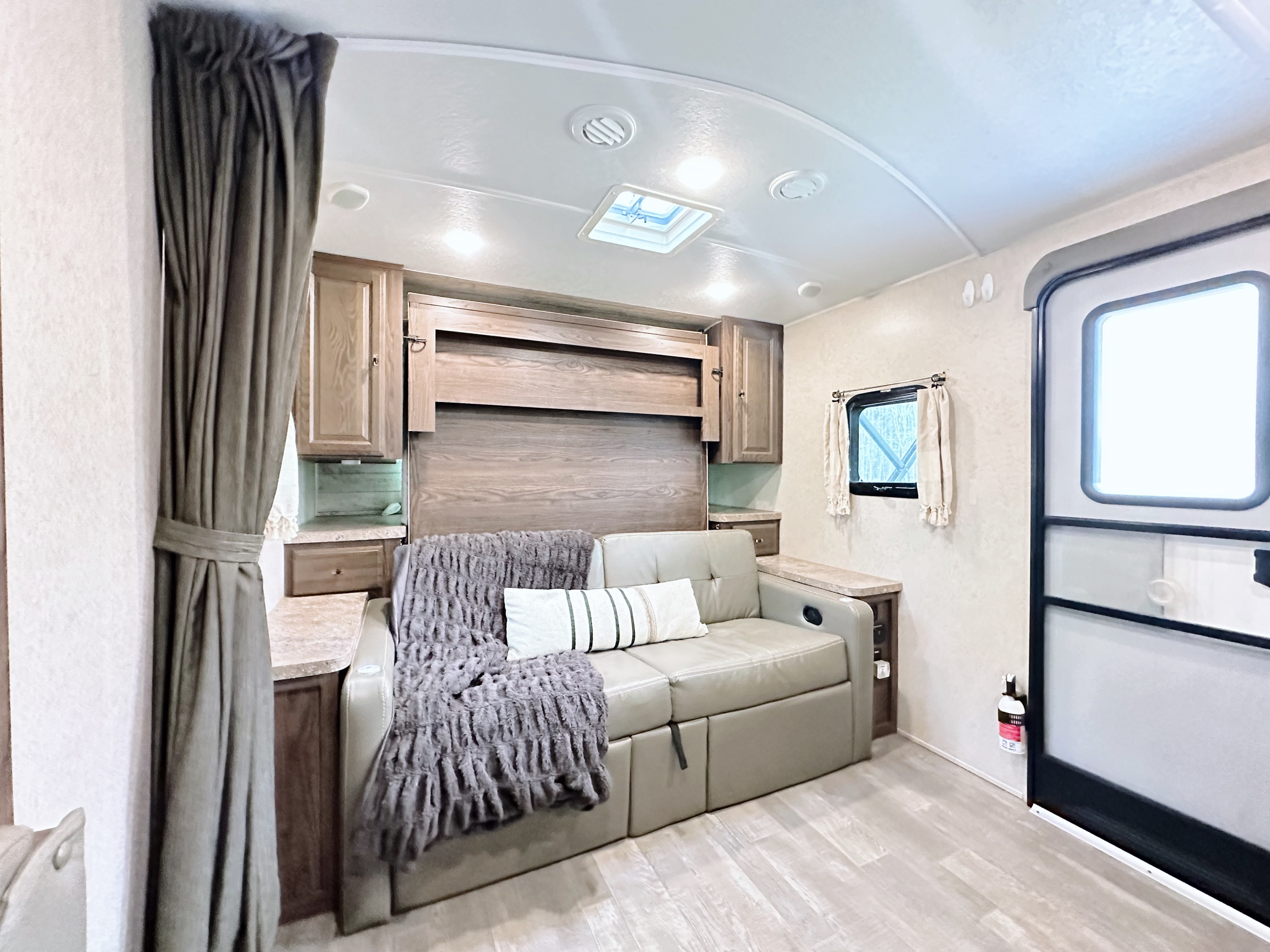 This RV rental offers a comfortable living area with a sofa, integrated pull-down bed, storage, and an entry door. Bright interior.. Forest River Flagstaff Micro Lite 2019