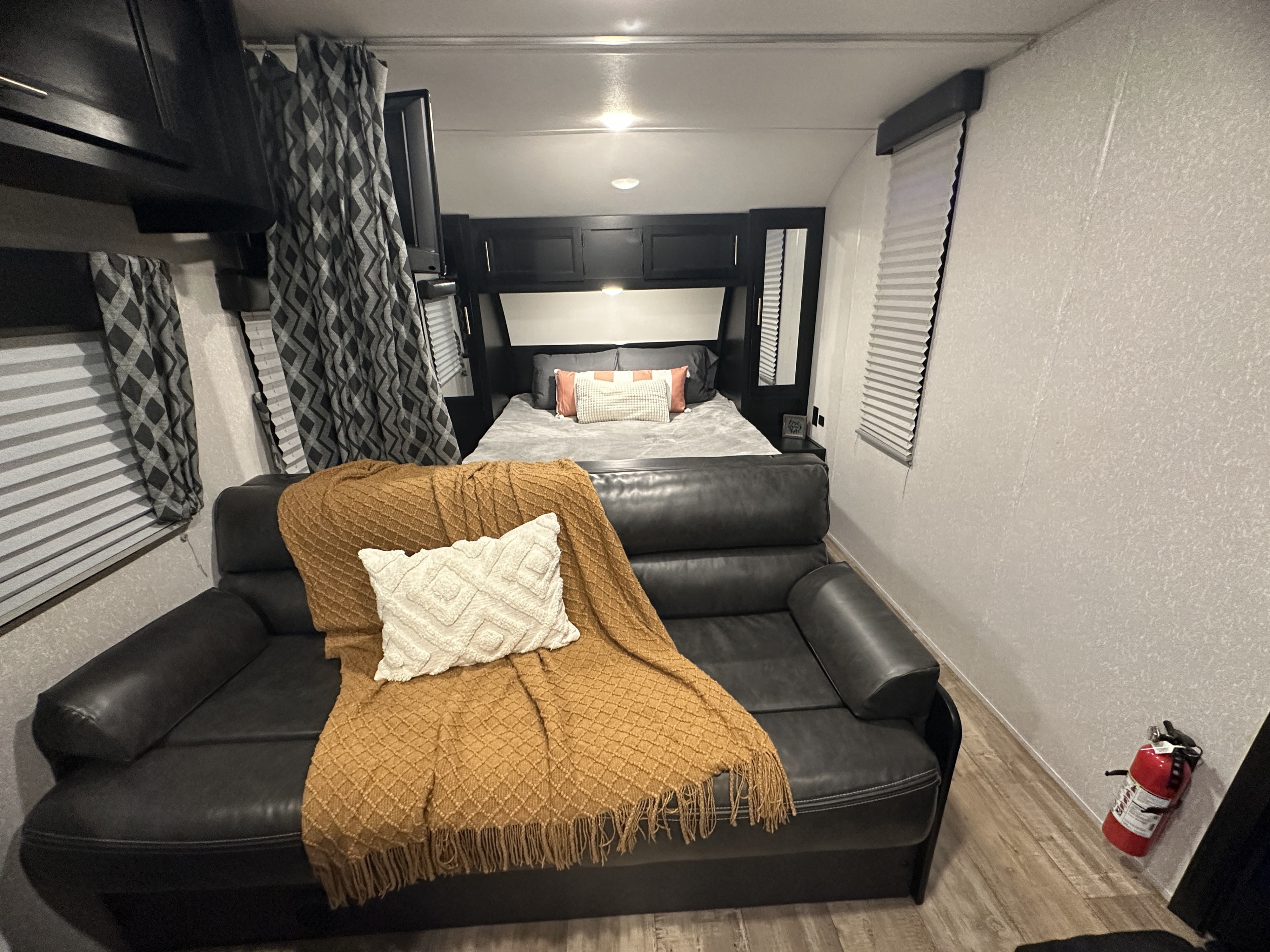 Inviting RV rental interior showing a comfortable couch, bed, and fire extinguisher, ready for a safe and relaxing trip.. Forest River Cherokee Grey Wolf Special Edition 2022