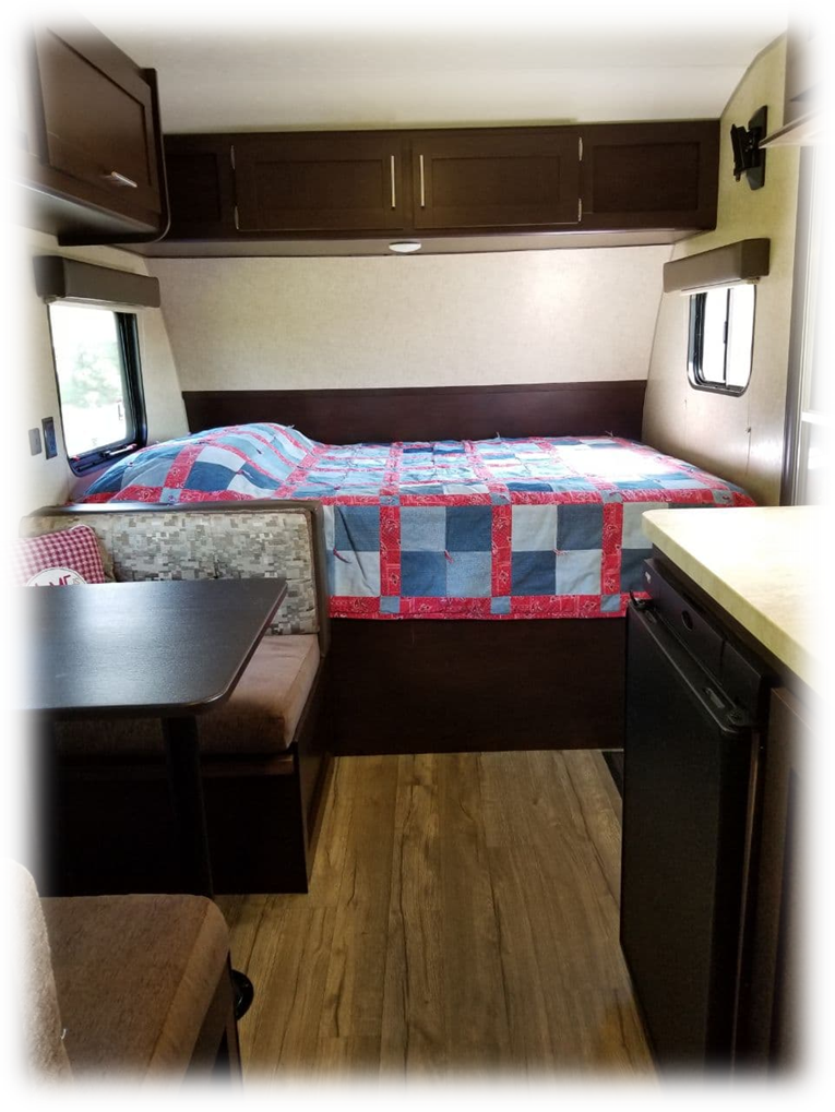 RV rental interior with a cozy bed, dinette, overhead cabinets, and wood-look flooring for compact travel.. Forest River Cherokee Wolf Pup 2018
