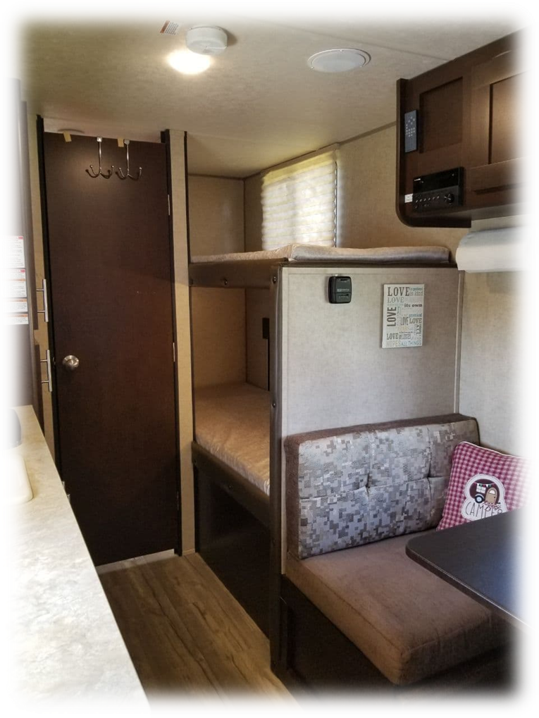 Inside an RV rental: a cozy dinette, stacked bunk beds, and kitchen counter for your next travel adventure.. Forest River Cherokee Wolf Pup 2018