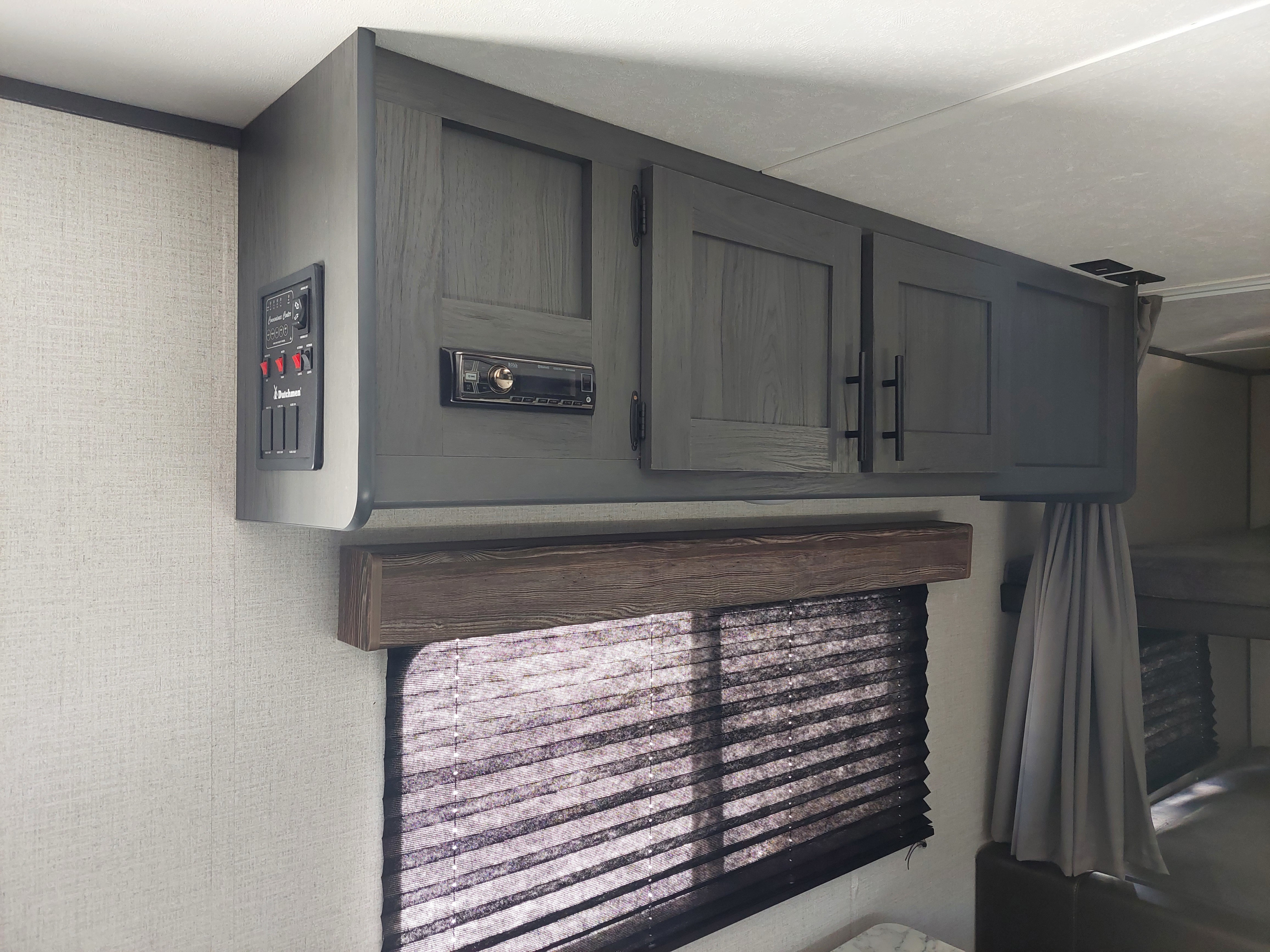 RV rental interior shows gray cabinets, control panel, stereo, window blinds, and bunk beds.. Aspen Trail LE 2022