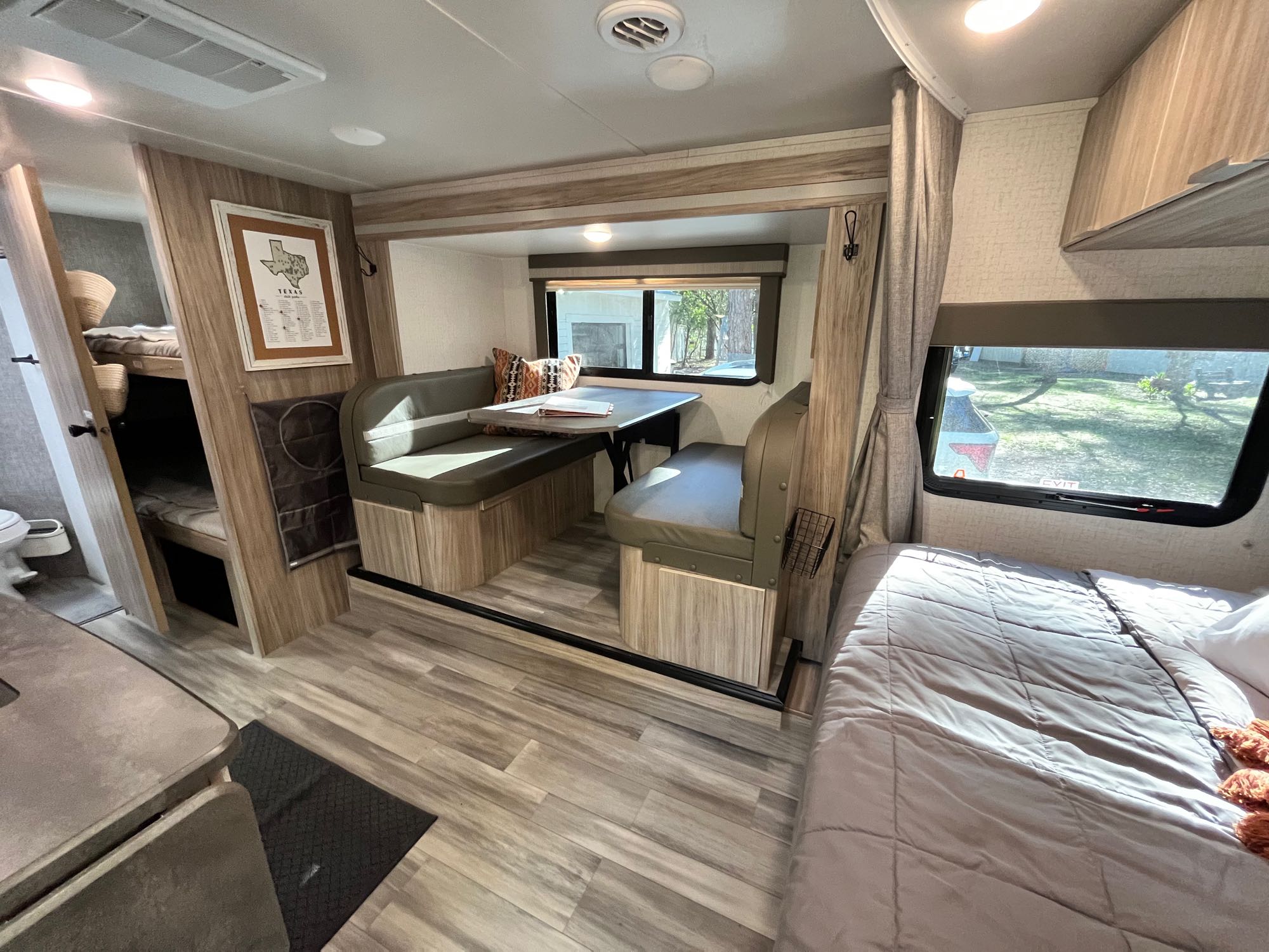 Interior of an RV rental featuring a dinette, main bed, bunk beds, kitchen, and partial bath. Bright and modern.. Winnebago Micro Minnie 2021