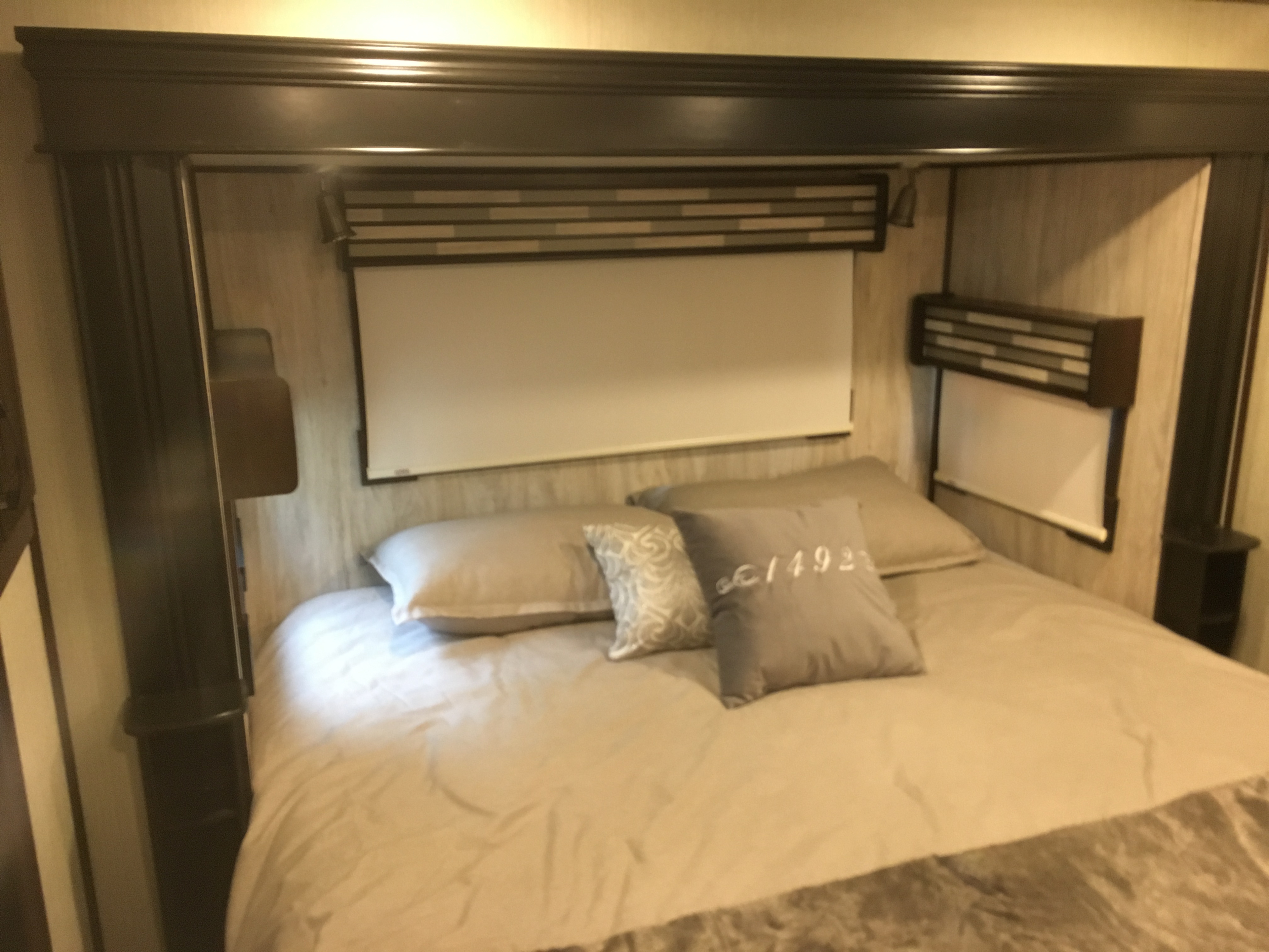 Cozy RV rental bedroom featuring a made bed with pillows, overhead storage, and window shades, offering comfort for travelers.. Forest River Palomino Columbus 2018