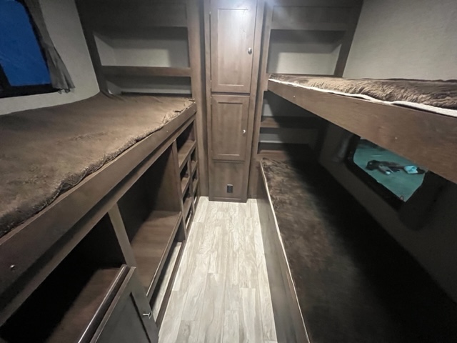 Spacious RV rental bunkhouse interior with four bunk beds, central storage, and wood-look flooring. Ready for family travel.. Forest River Shasta Oasis 2018