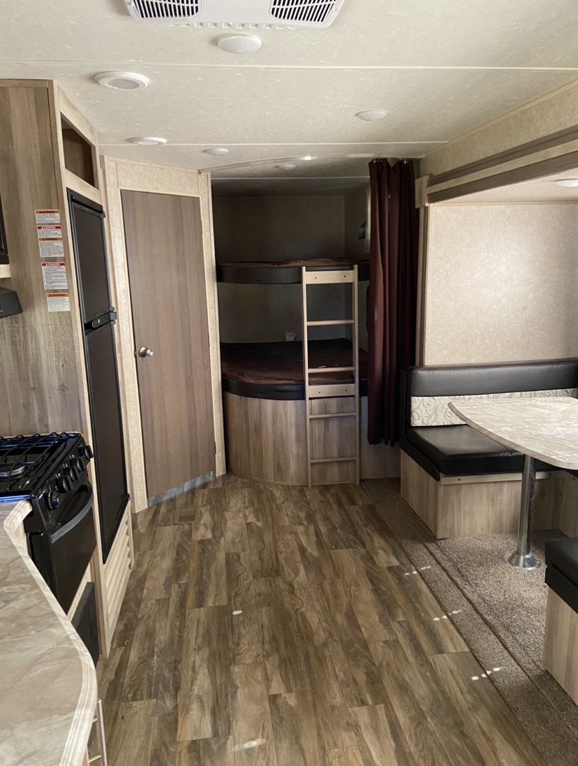 RV rental interior: kitchen with stove, refrigerator, separate bunk beds, and dinette area. Features wood flooring.. Forest River Coachmen Catalina SBX 2020