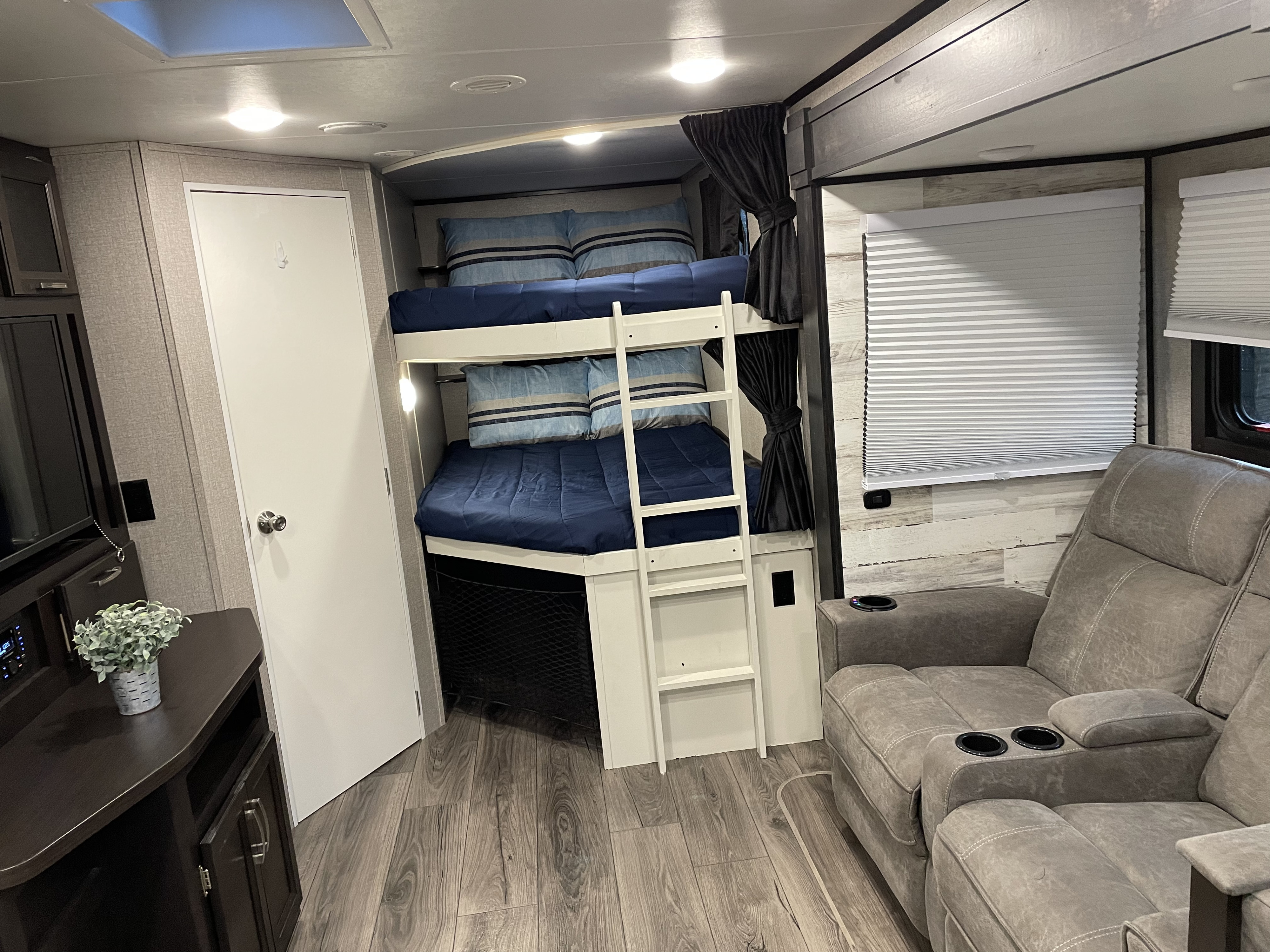 This inviting RV rental interior features cozy bunk beds, a comfy recliner sofa, and modern decor for your travel adventures.. Jayco Jay Feather 2021