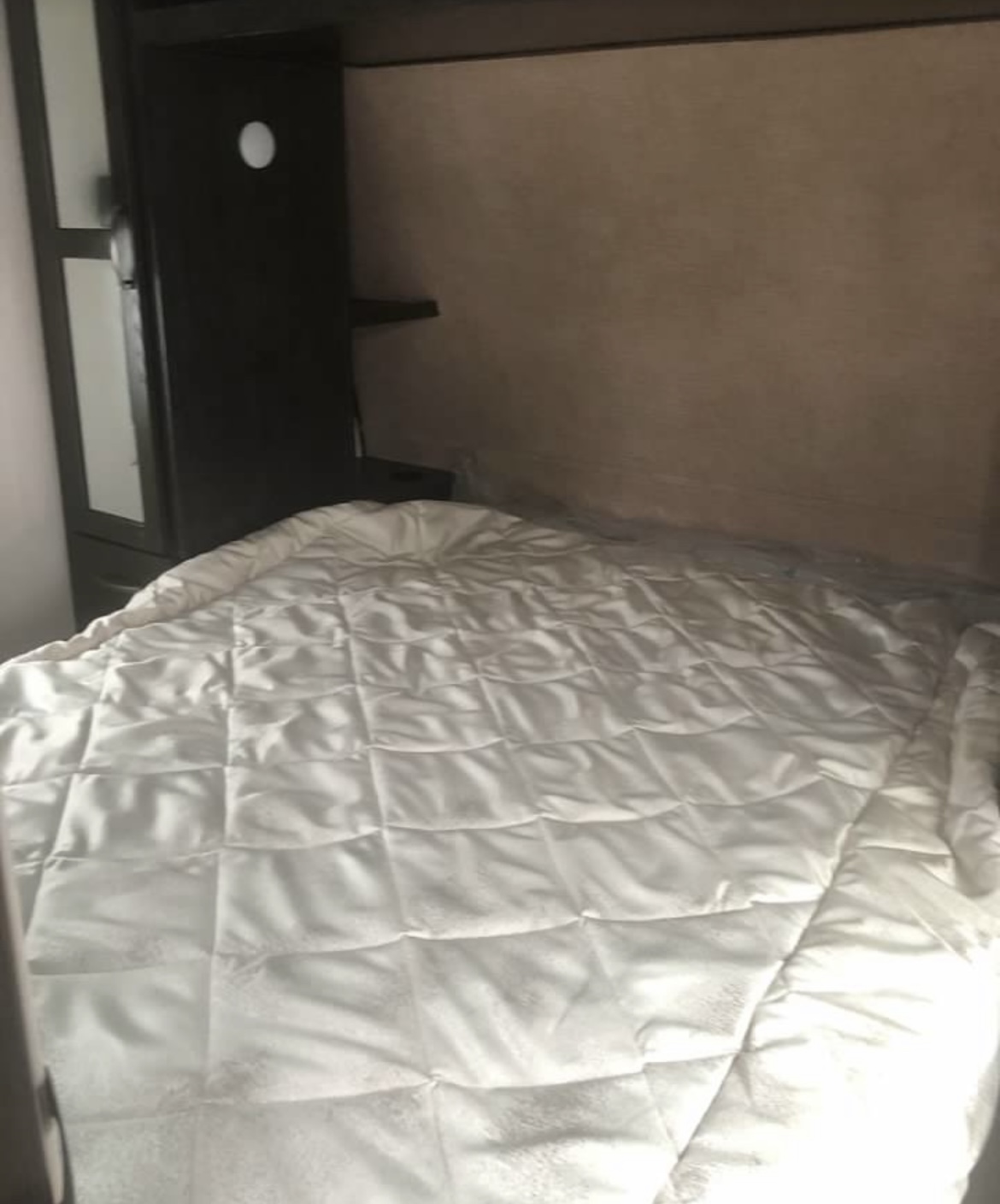 Cozy white bed setup in an RV rental. Features a comfortable sleeping area with compact storage.. Forest River Surveyor Legend 2019