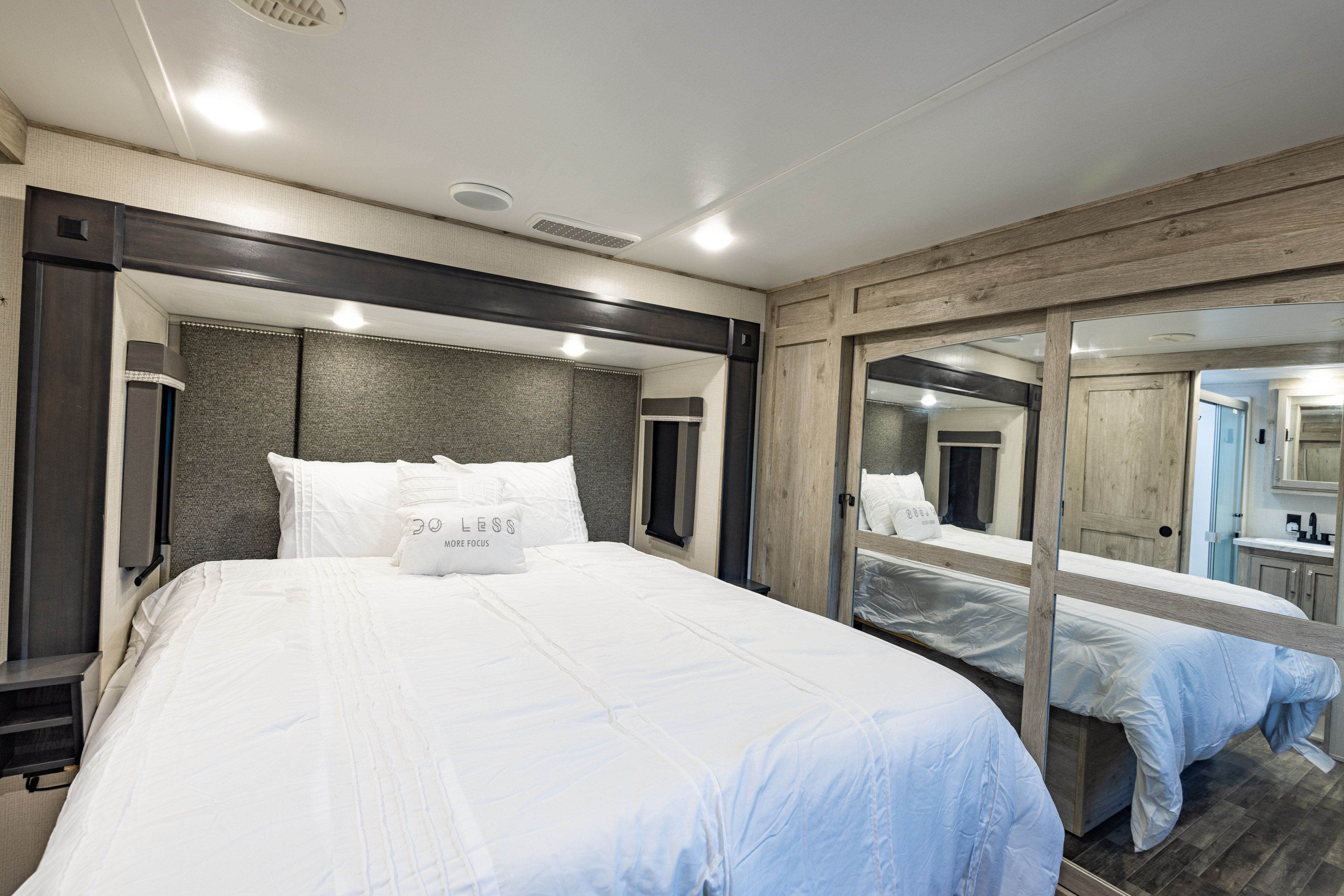 This comfortable RV rental bedroom features a plush bed, mirrored wardrobe, and modern interior for relaxing travels.. Keystone RV Avalanche 2021