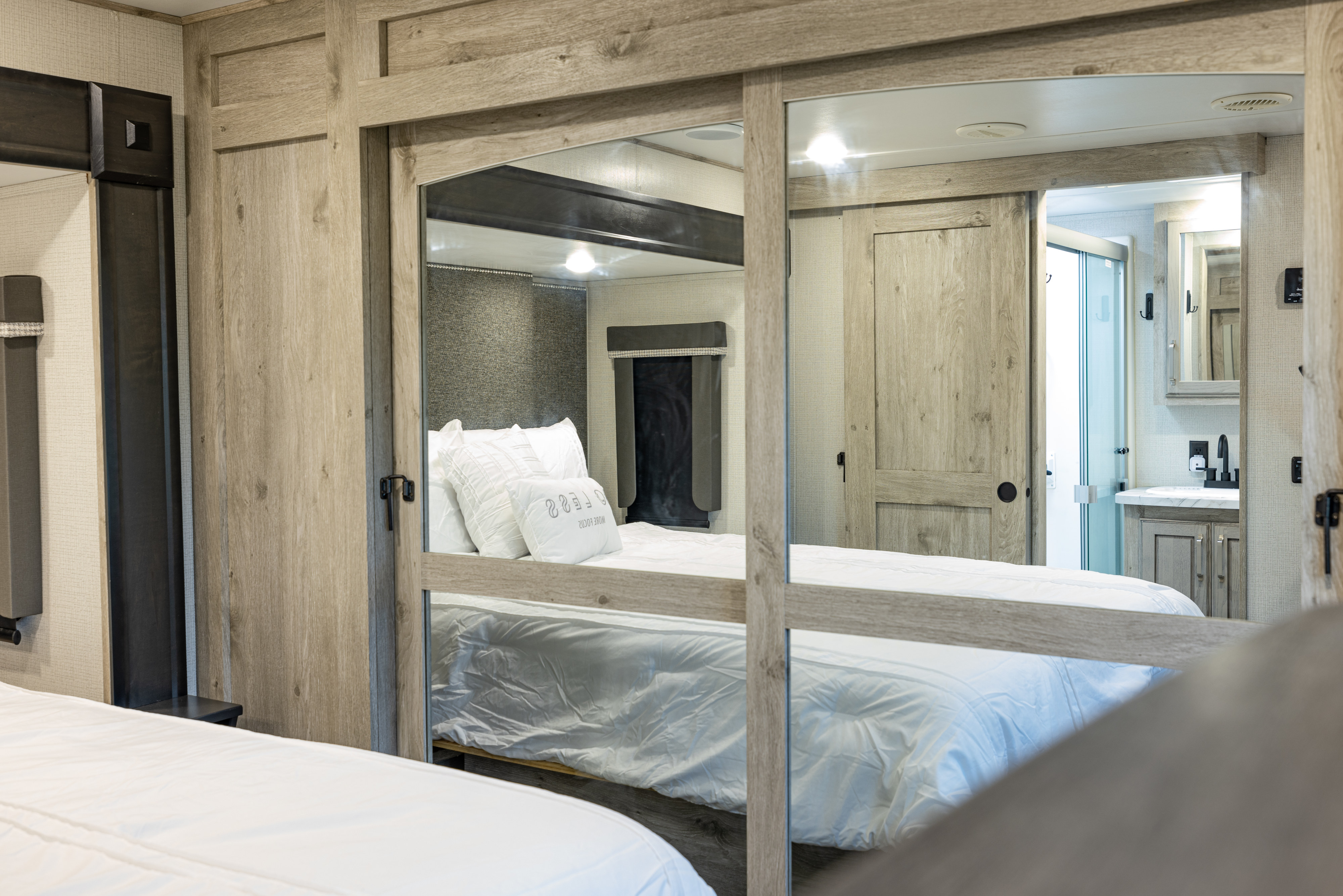 RV rental bedroom with a mirrored closet reflecting a modern bathroom, offering comfort and convenience.. Keystone RV Avalanche 2021