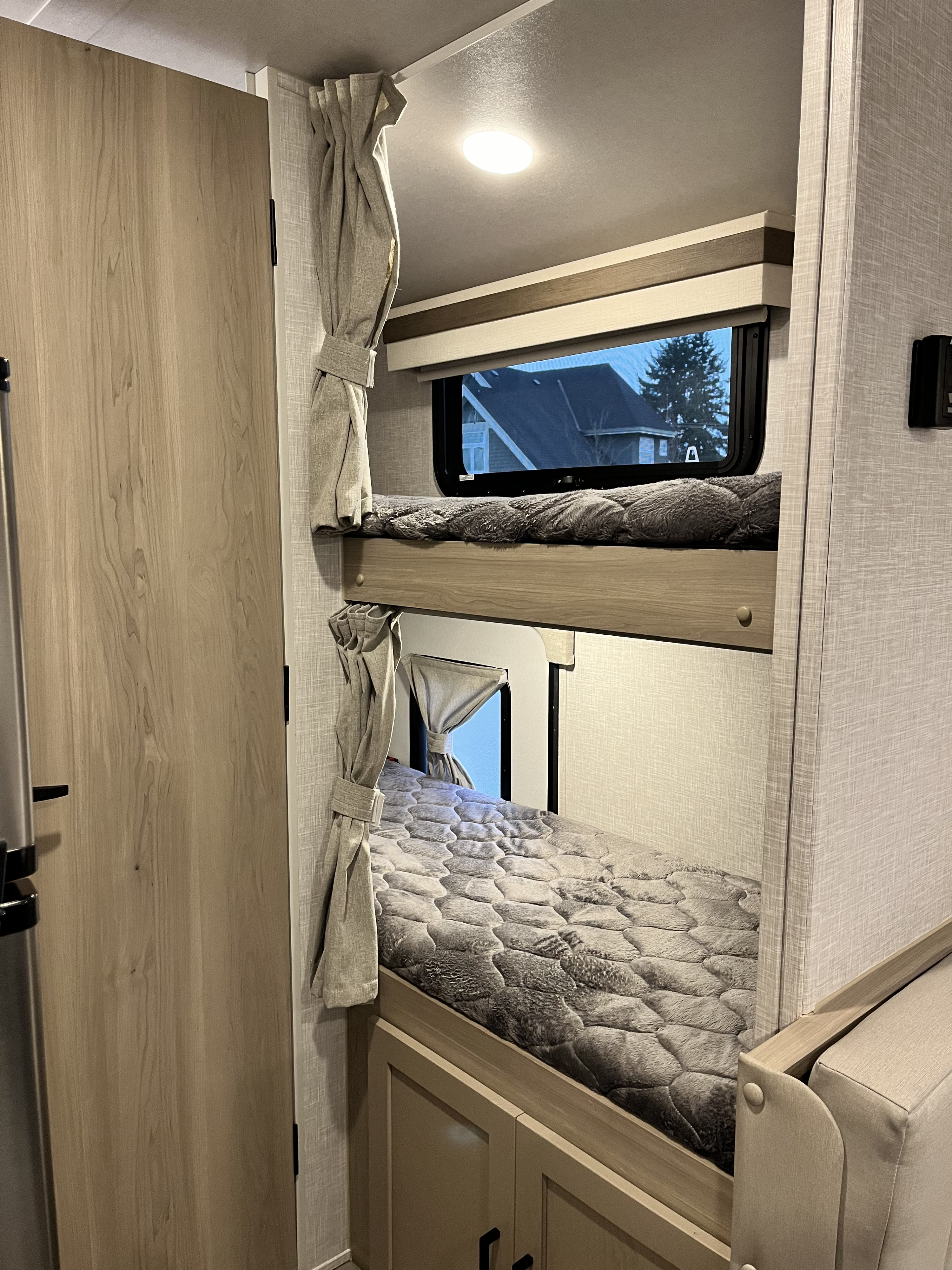 Inside an RV rental: a stack of bunk beds with soft gray comforters, windows, and light wood cabinetry.. Forest River Geo Pro 19BH (bunk house) 2023