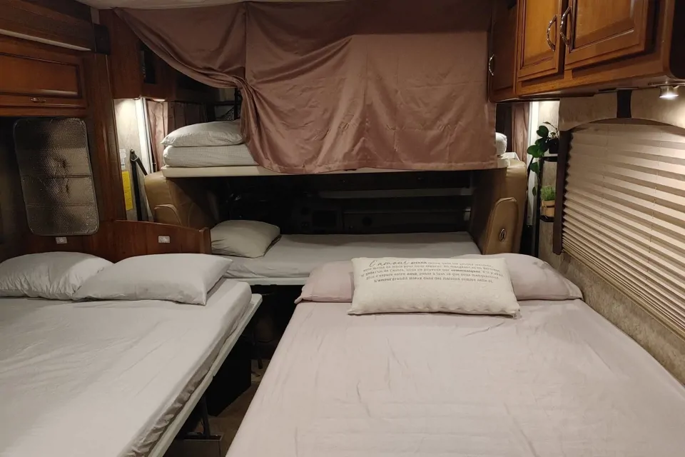 RV rental interior showing multiple bunk beds and floor beds, maximizing sleeping space for travelers.. Fleetwood Storm 2014