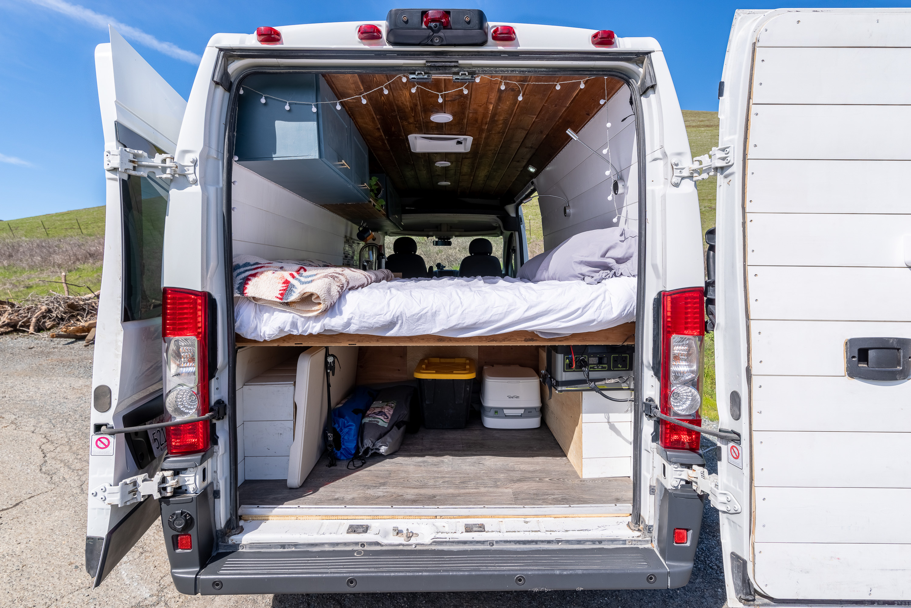 Explore van life in this cozy RV rental! Rear view shows a custom camper van interior with bed, storage, and power station.. Ram Promaster 2500 2014