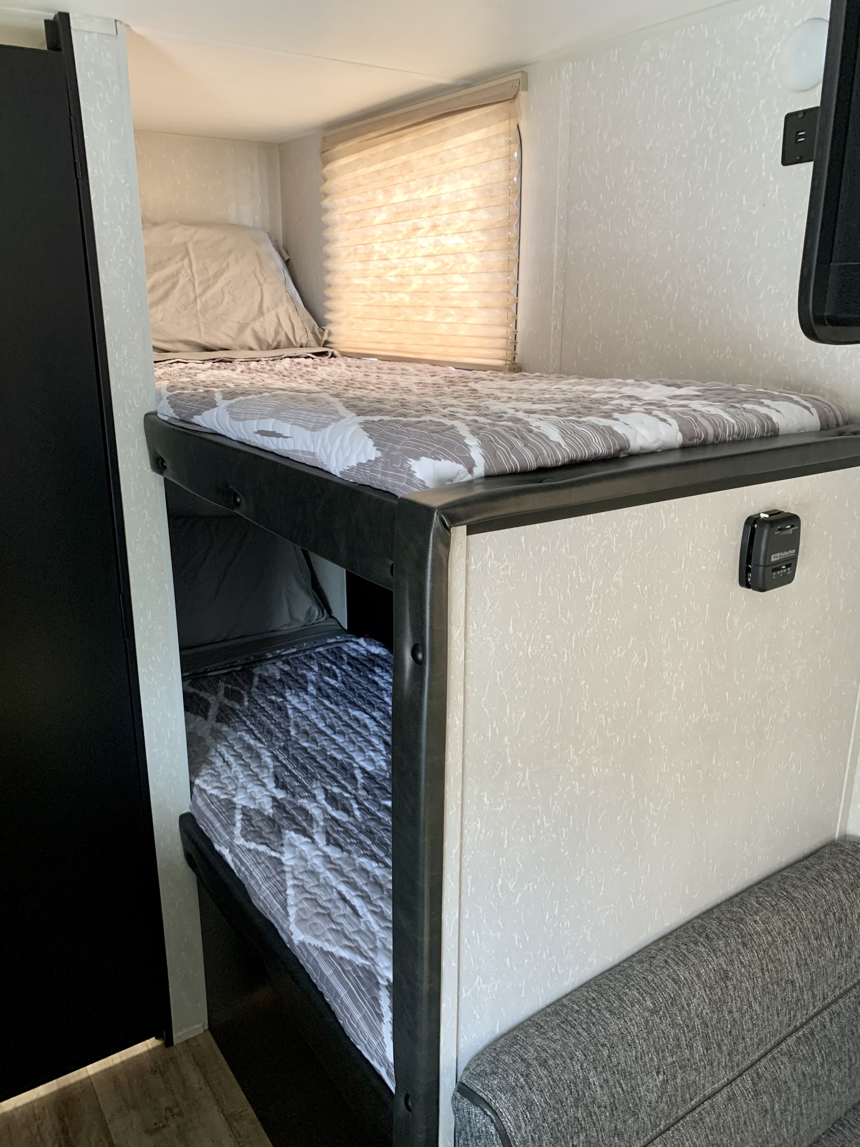 Cozy bunk beds in an RV rental, complete with soft quilts, a window, and thermostat control for a comfortable stay.. Forest River Cherokee Wolf Pup 2021